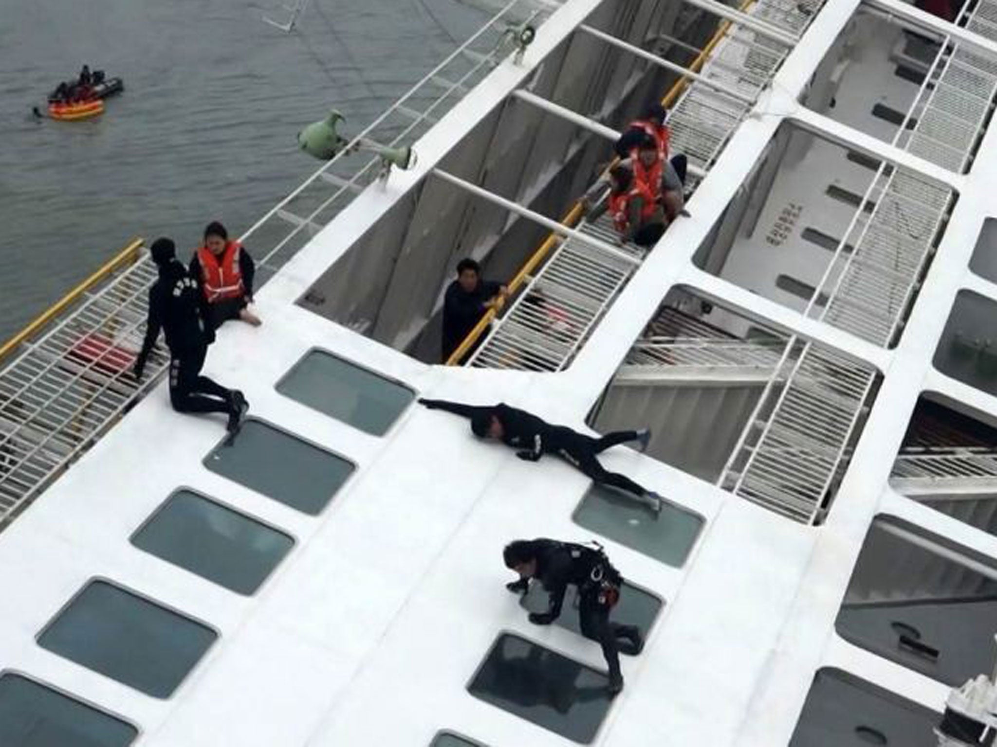 Maritime officers (in black) try to rescue passengers (in orange coloured life vests) onboard South Korean ferry "Sewol" which capsized off Jindo April 16
