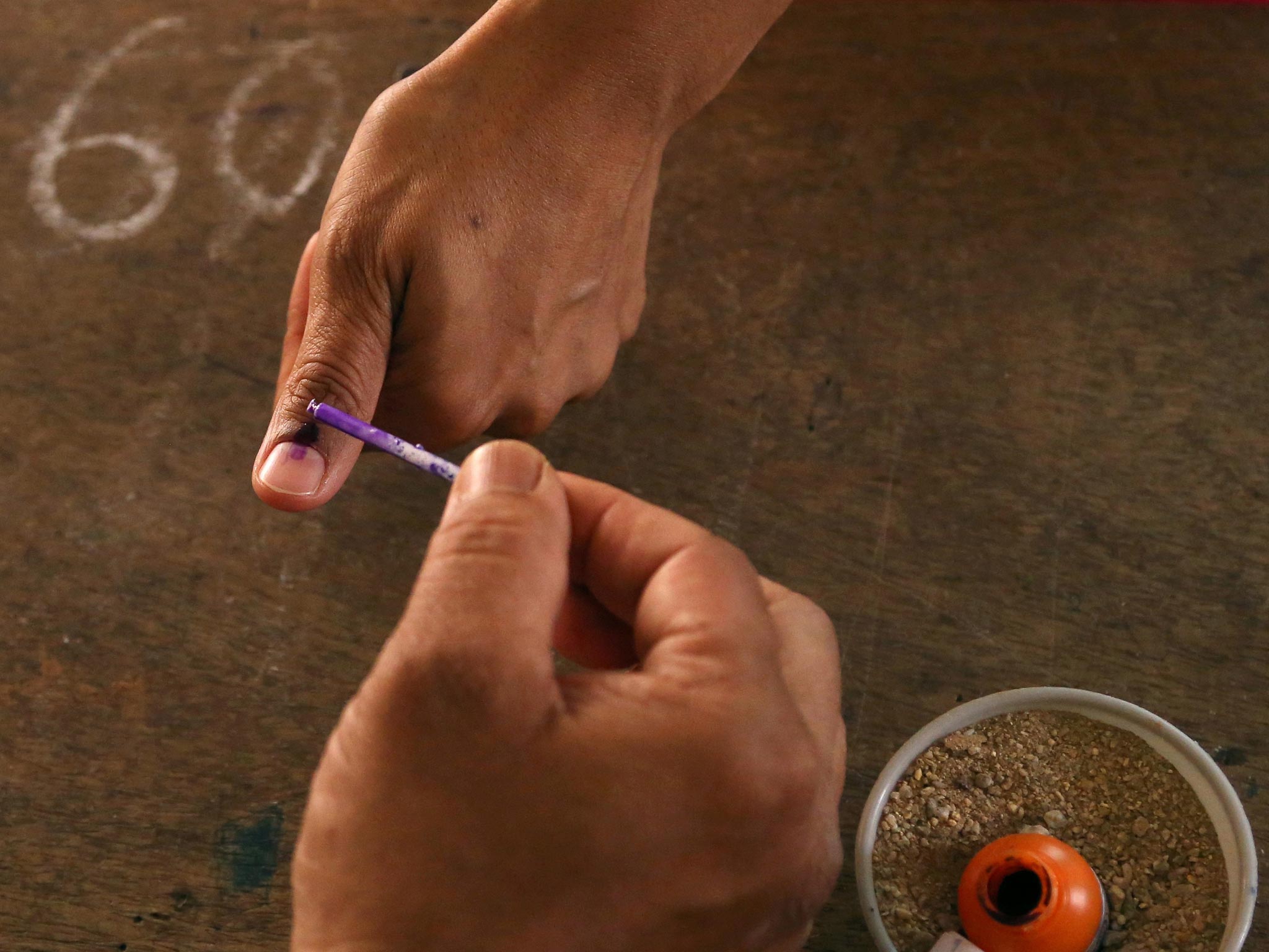 A polling officer marks the finger of a voter with indelible ink at a polling station in Bangalore, India