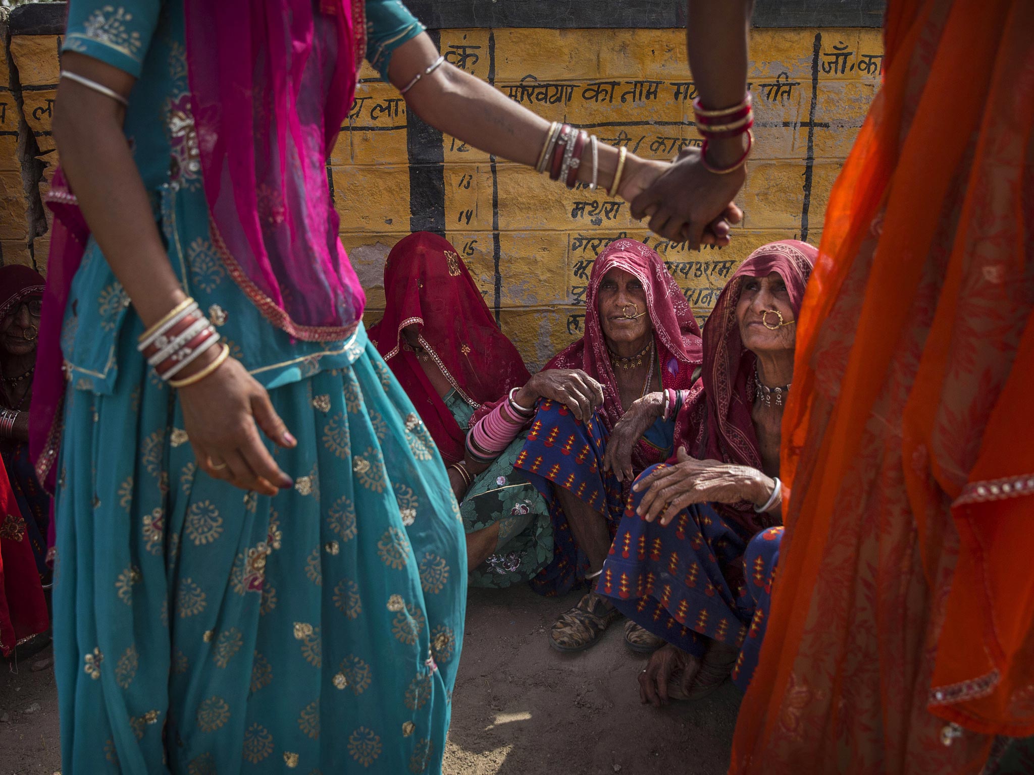 Indian women wait to vote at a polling station in the Jodhpur District in the desert state of Rajasthan, India