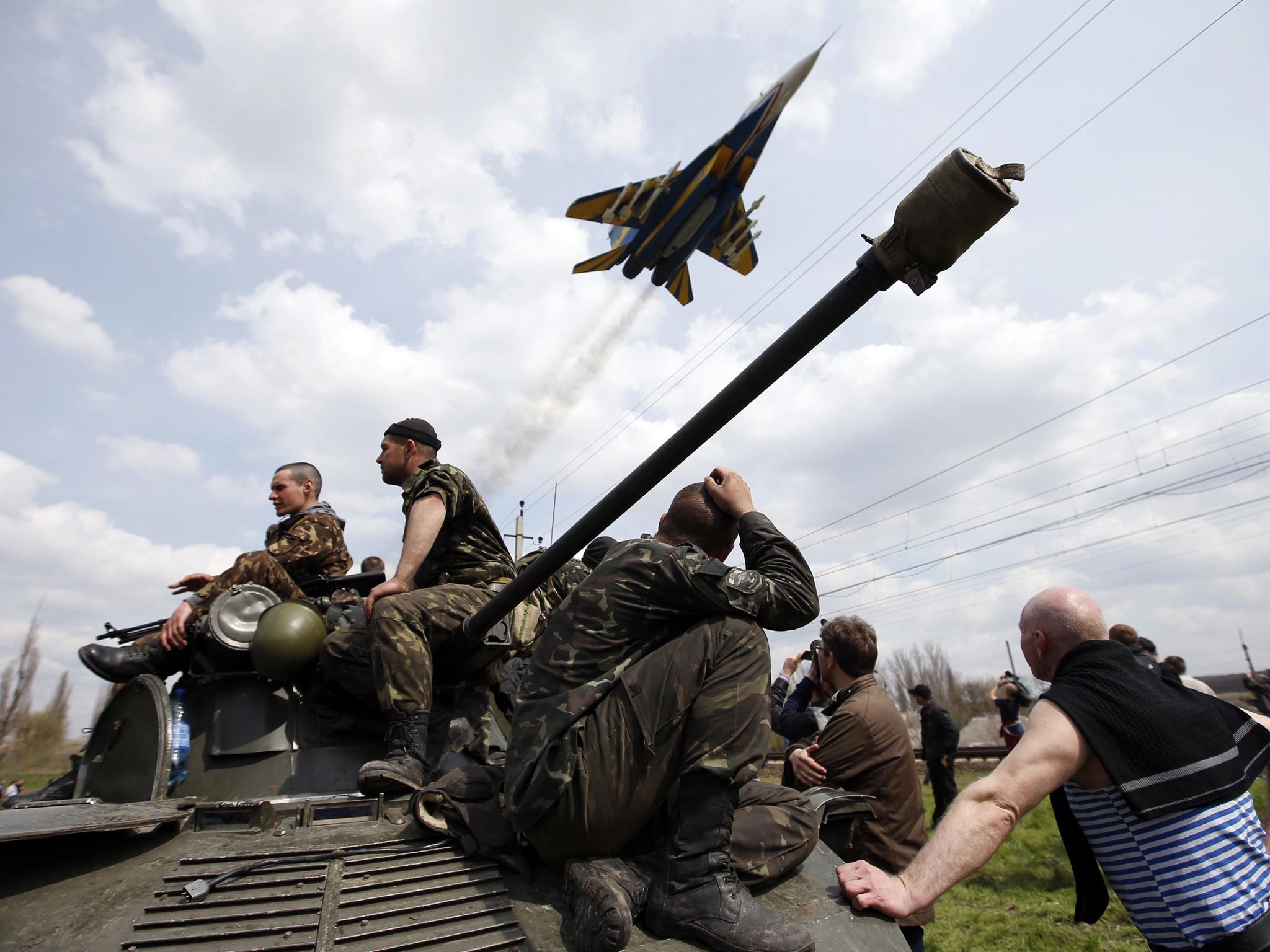 A fighter jet flies above as Ukrainian soldiers sit on an armoured personnel carrier in Kramatorsk, Ukraine