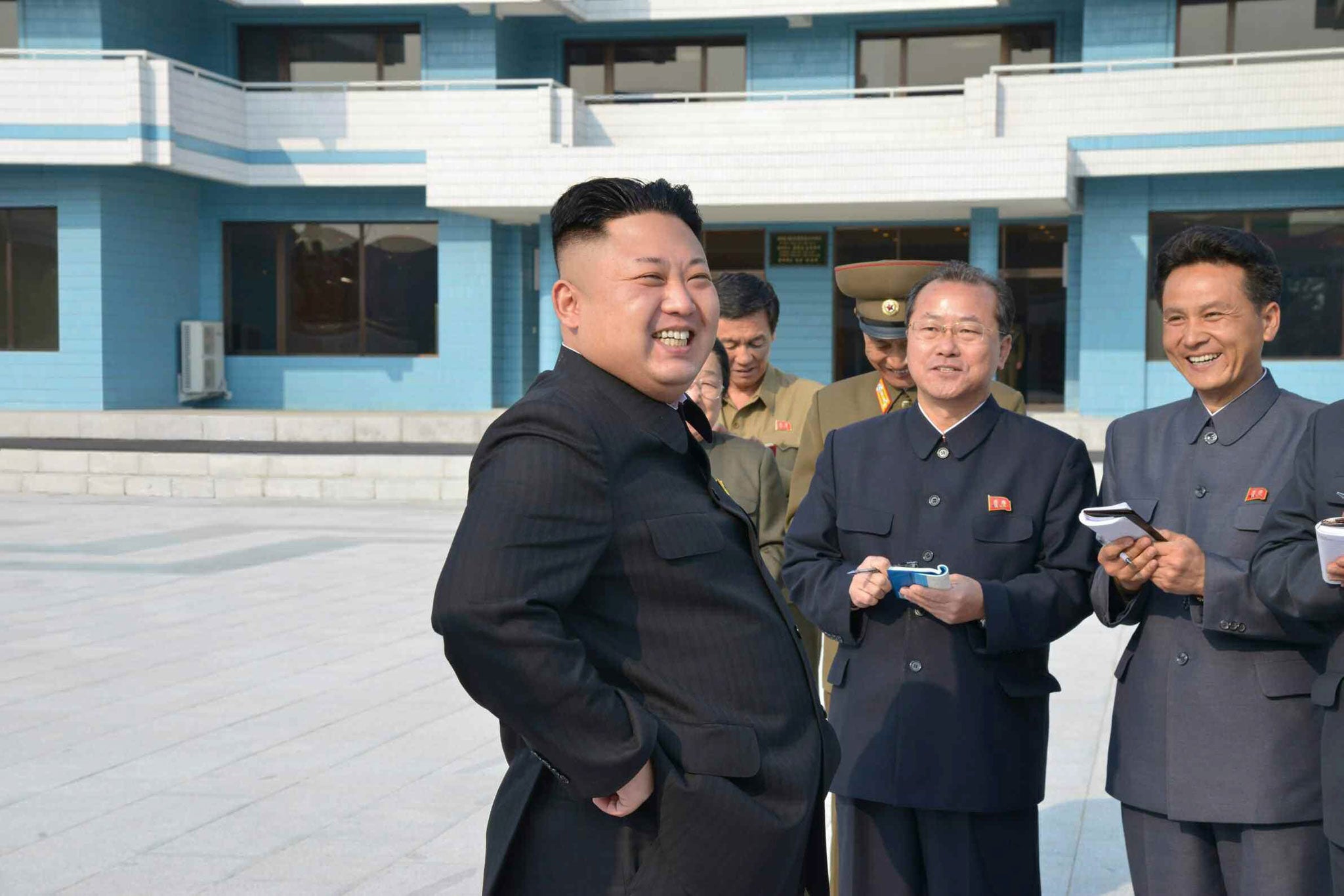 Kim Jong-un smiling broadly along with other officials during his visit to a youth camping site in Wonsan on the southeastern coast in North Korea