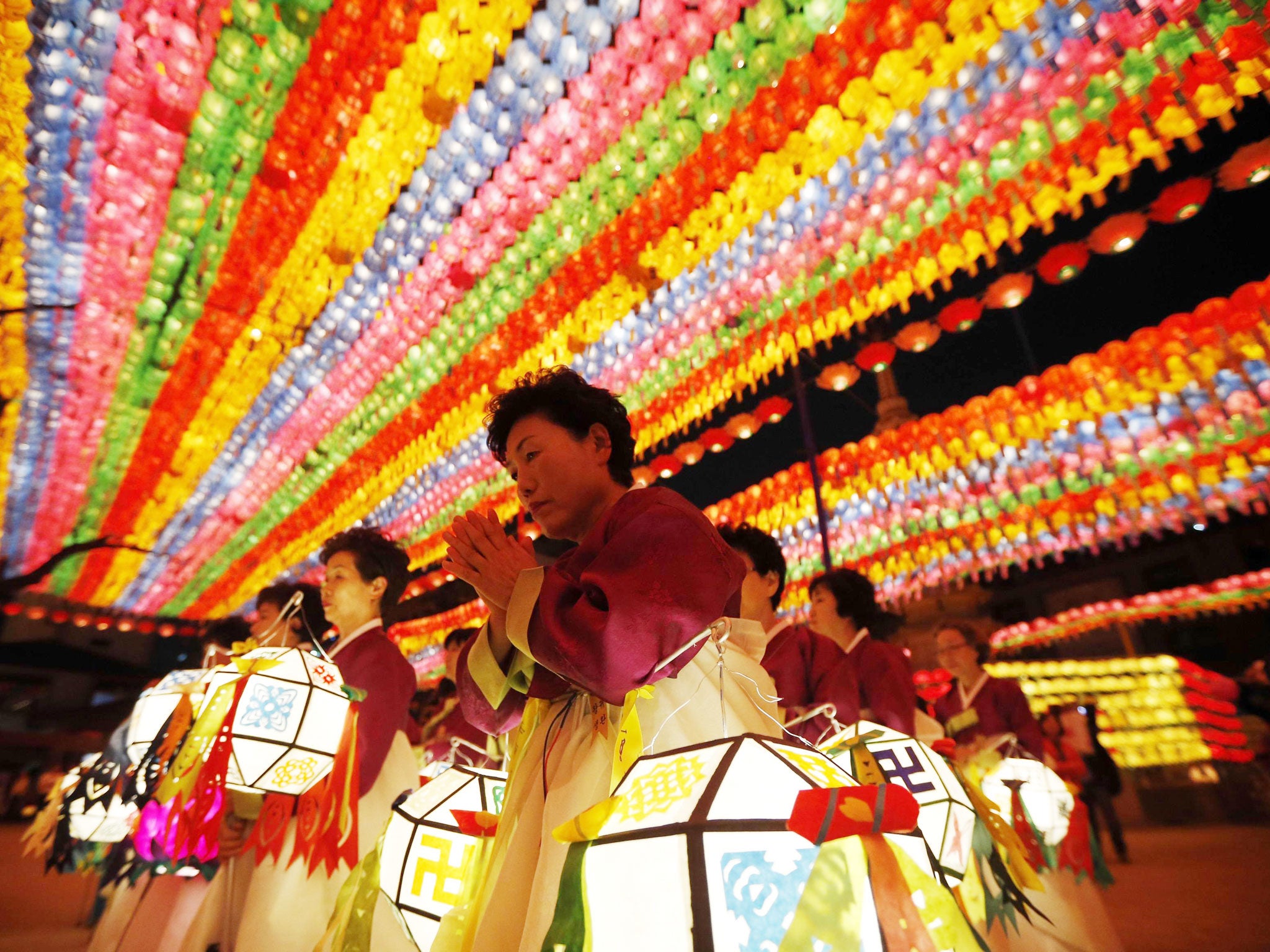 Buddhist believers holding lanterns pray after a lotus lantern parade to celebrate the upcoming birthday of Buddha and to commemorate the victims of the capsized passenger ship Sewol, at Jogye temple in Seoul