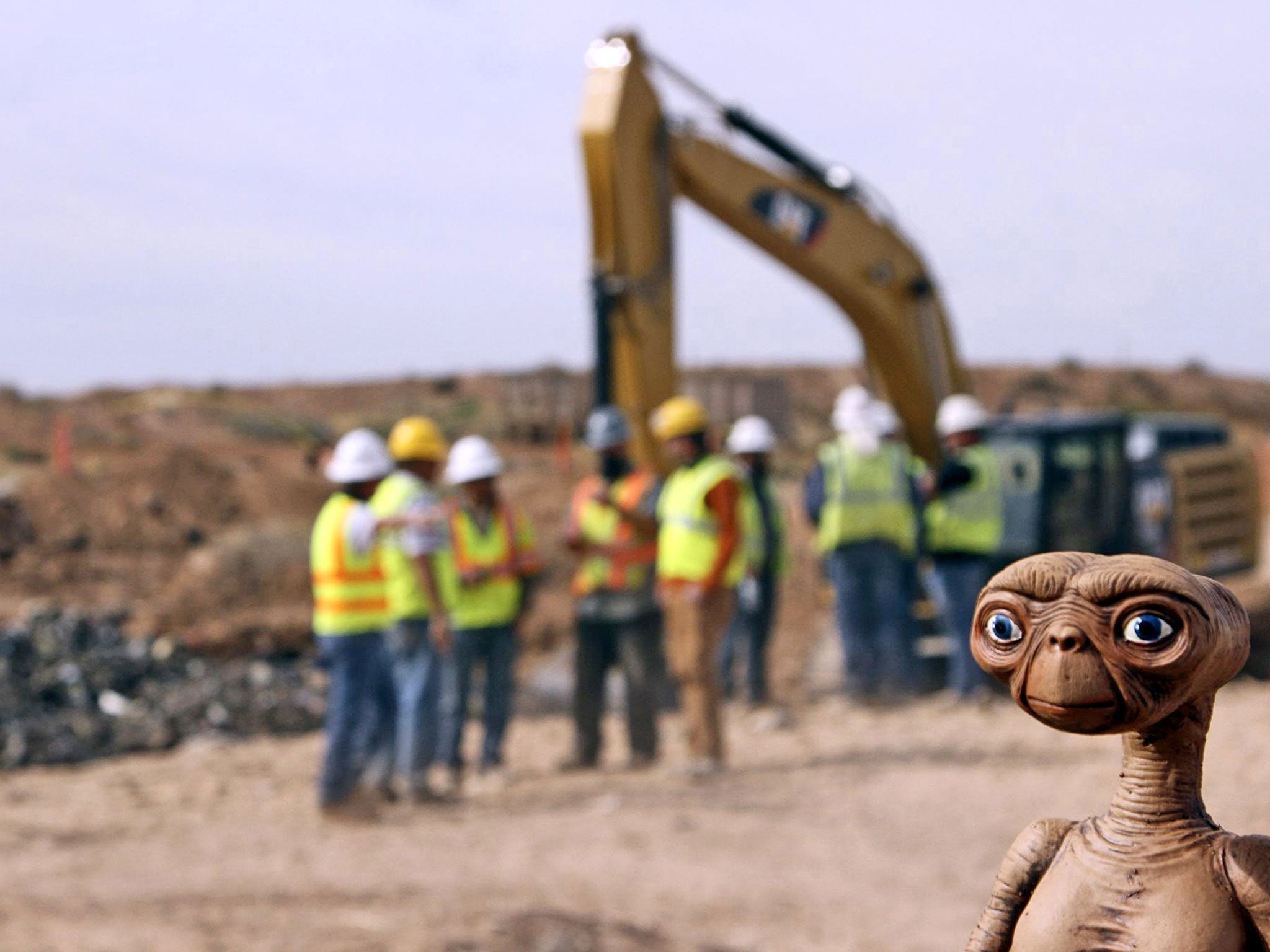 Game not over: an E.T. doll looks on as workmen uncover the dumped cartridges