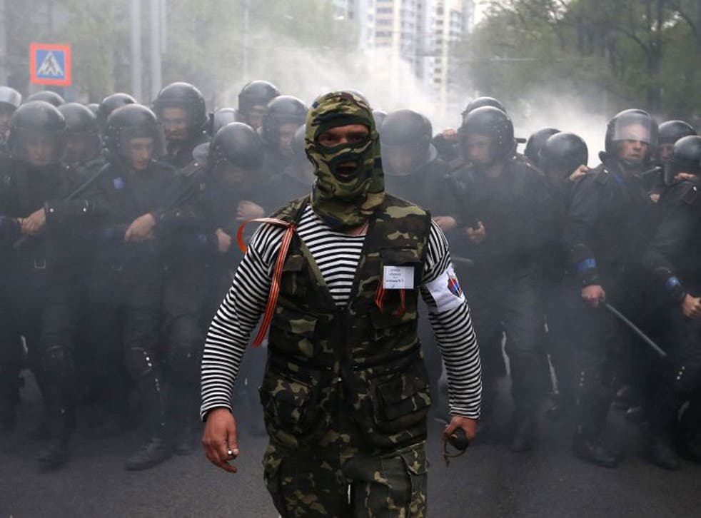 A pro-Russian activist walks in front of Ukrainian riot police during a rally in Donetsk