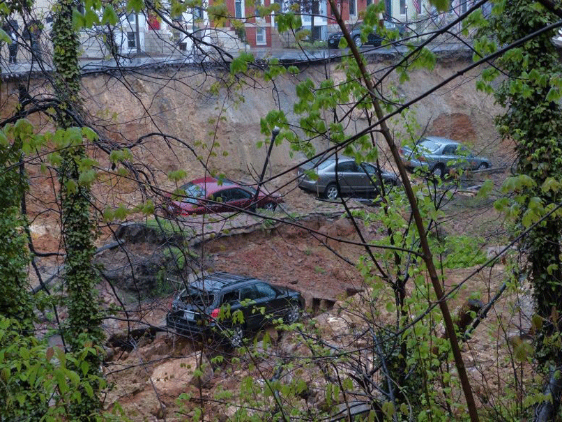 Cars sit on the edge of a sinkhole in the Charles Village neighborhood of Baltimore on Wednesday April 30, 2014.