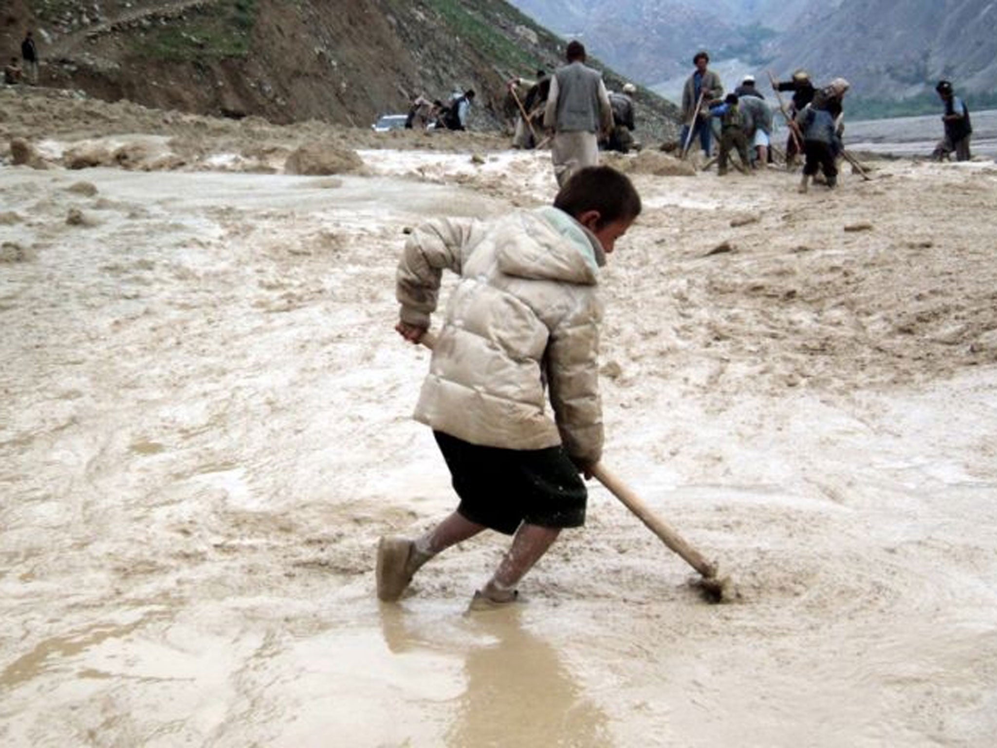 Workers removing debris from a road affected by flash floods in Badakhshan, Afghanistan. As in 2012, the area has been hit again by a comparable disaster. At least 2,100 people are feared dead on 02 May 2014, after a mudslide, caused by heavy rainfalls, b