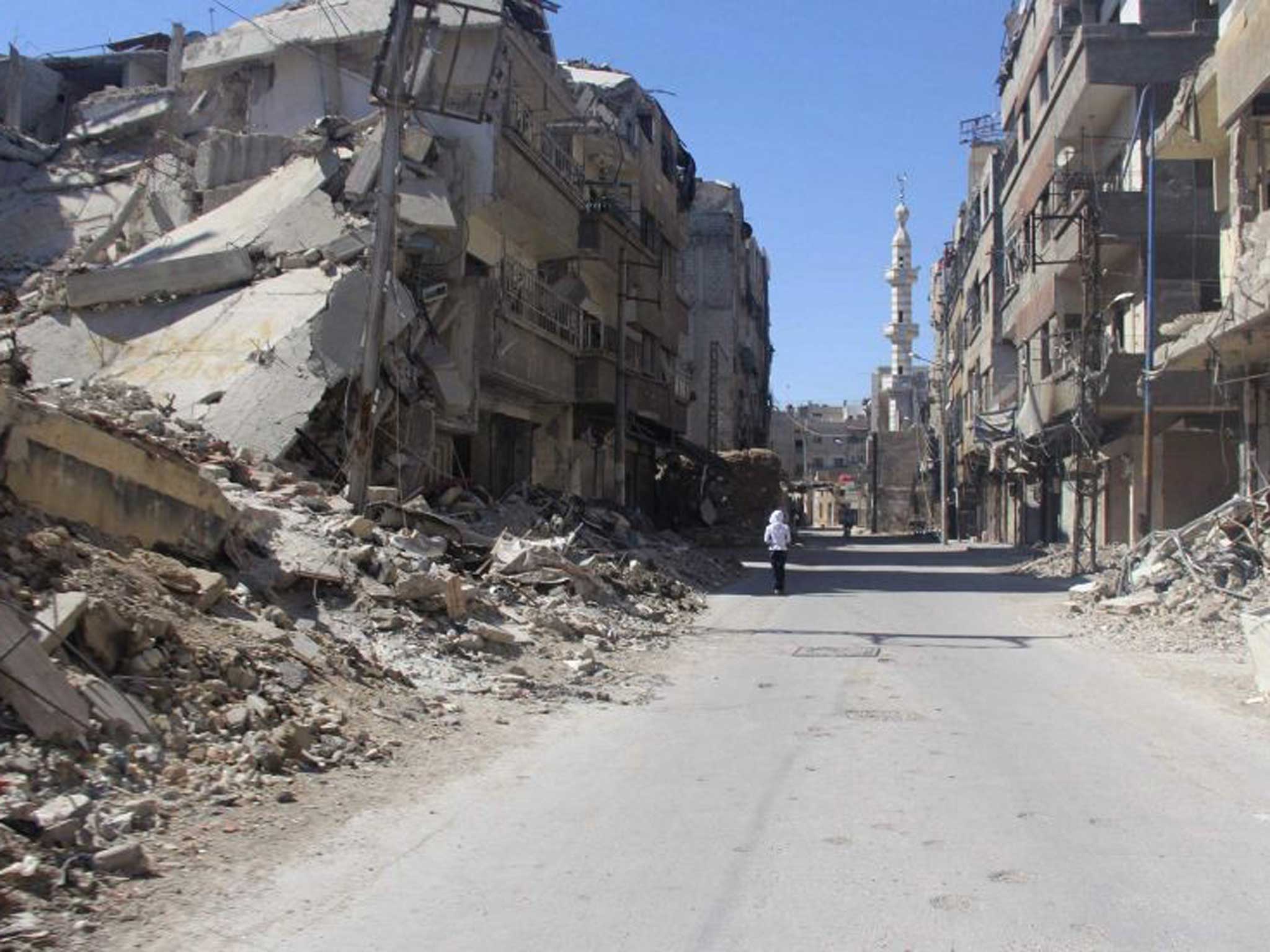 A resident walks alone down a ruined Damascus street