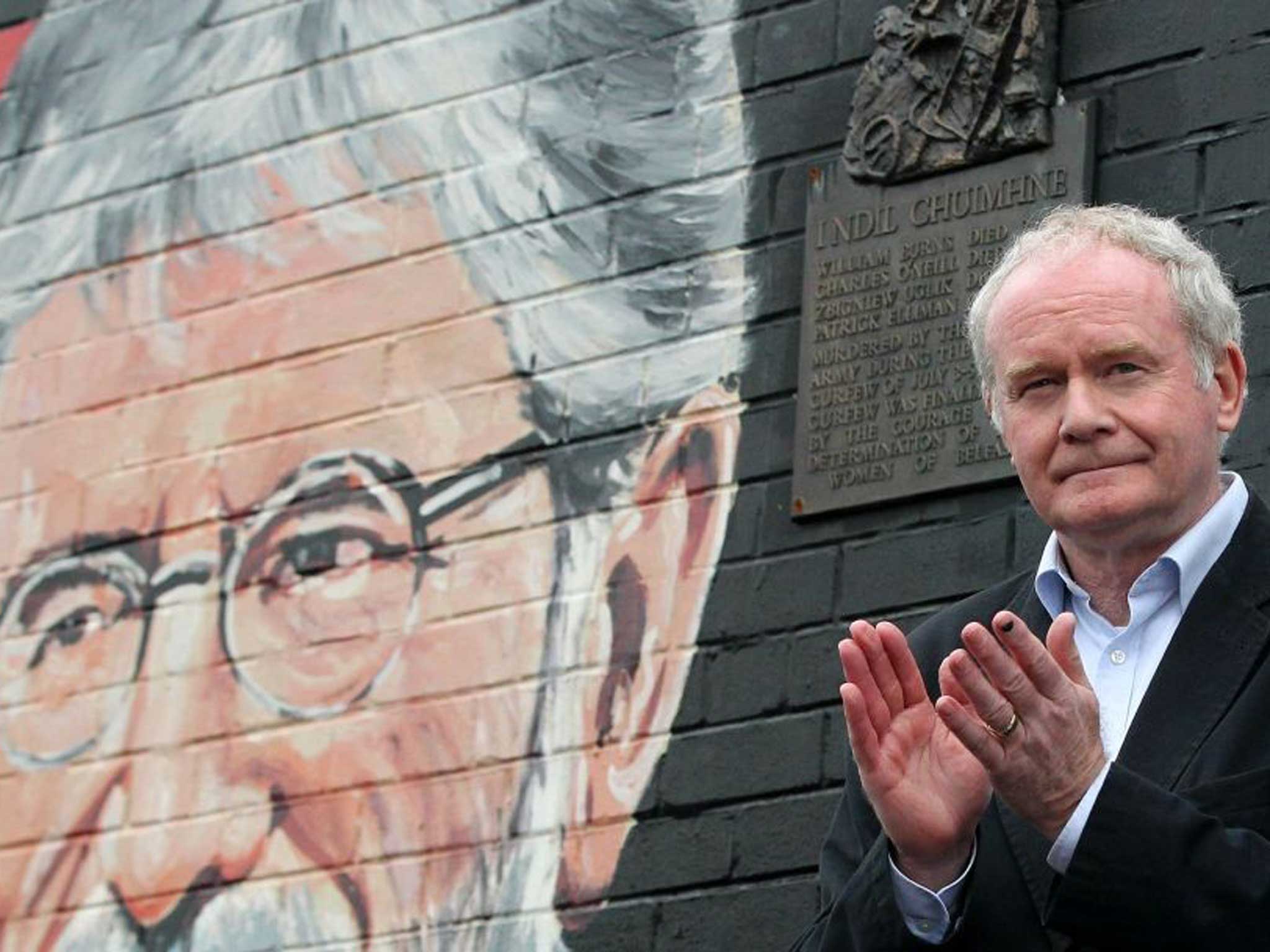 Deputy Martin McGuinness applauds the crowd as he speaks against a backdrop of a mural of detained Sinn Fein leader Gerry Adams
