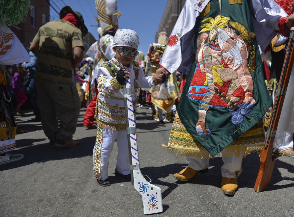 A boy dressed in carnival attire waits with his father before the Carnaval de Puebla, a traditional Mexican carnival celebration that re-enacts the Battle of Cinco de Mayo