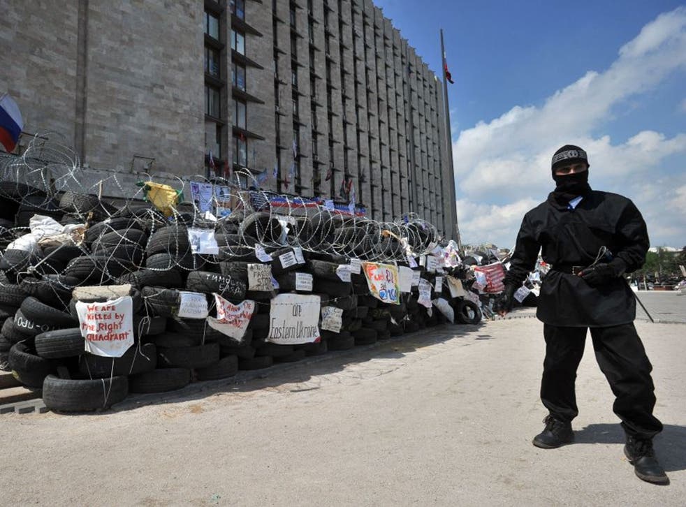 A pro-Russian militant guards a barricade outside the seized regional state building in the eastern Ukrainian city of Donetsk on May 5, 2014. Four Ukrainian troops were killed and 30 wounded in intense fighting around the rebel-held town of Slavyansk on May 5, the interior ministry said. The ministry added that the pro-Russian gunmen controlling the town were using civilians as human shields and were shooting from houses, some of which were on fire. It said there were civilian casualties but did not provide a toll.