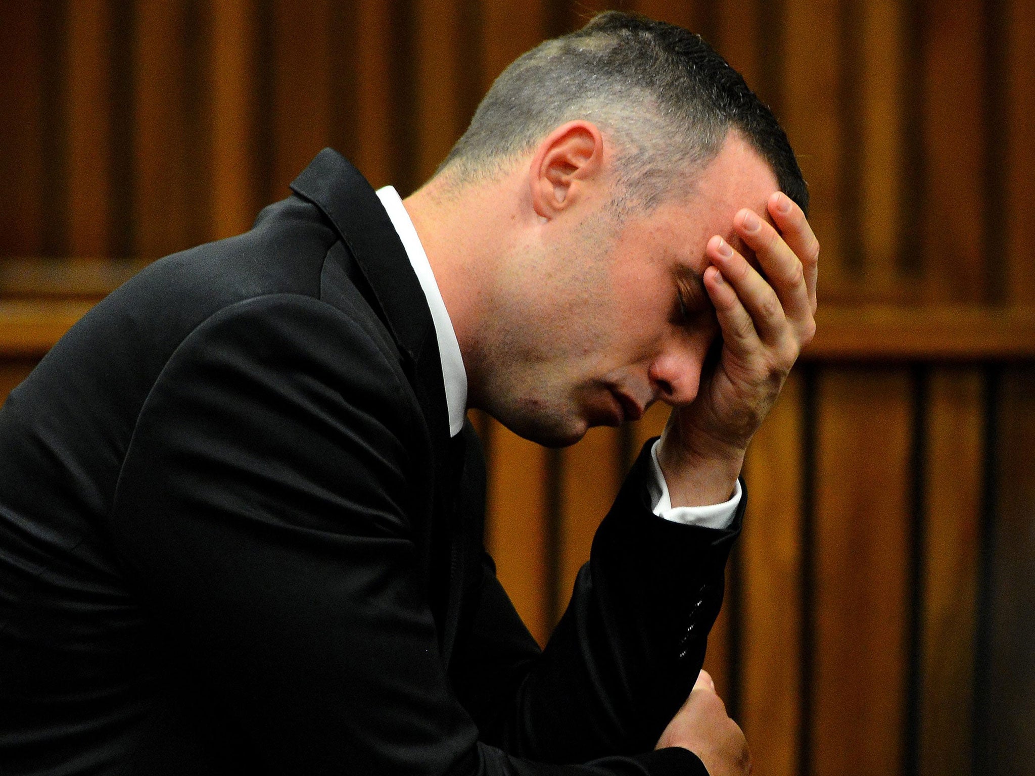 Oscar Pistorius holds his hand on his forehead in the dock at the high court in Pretoria
