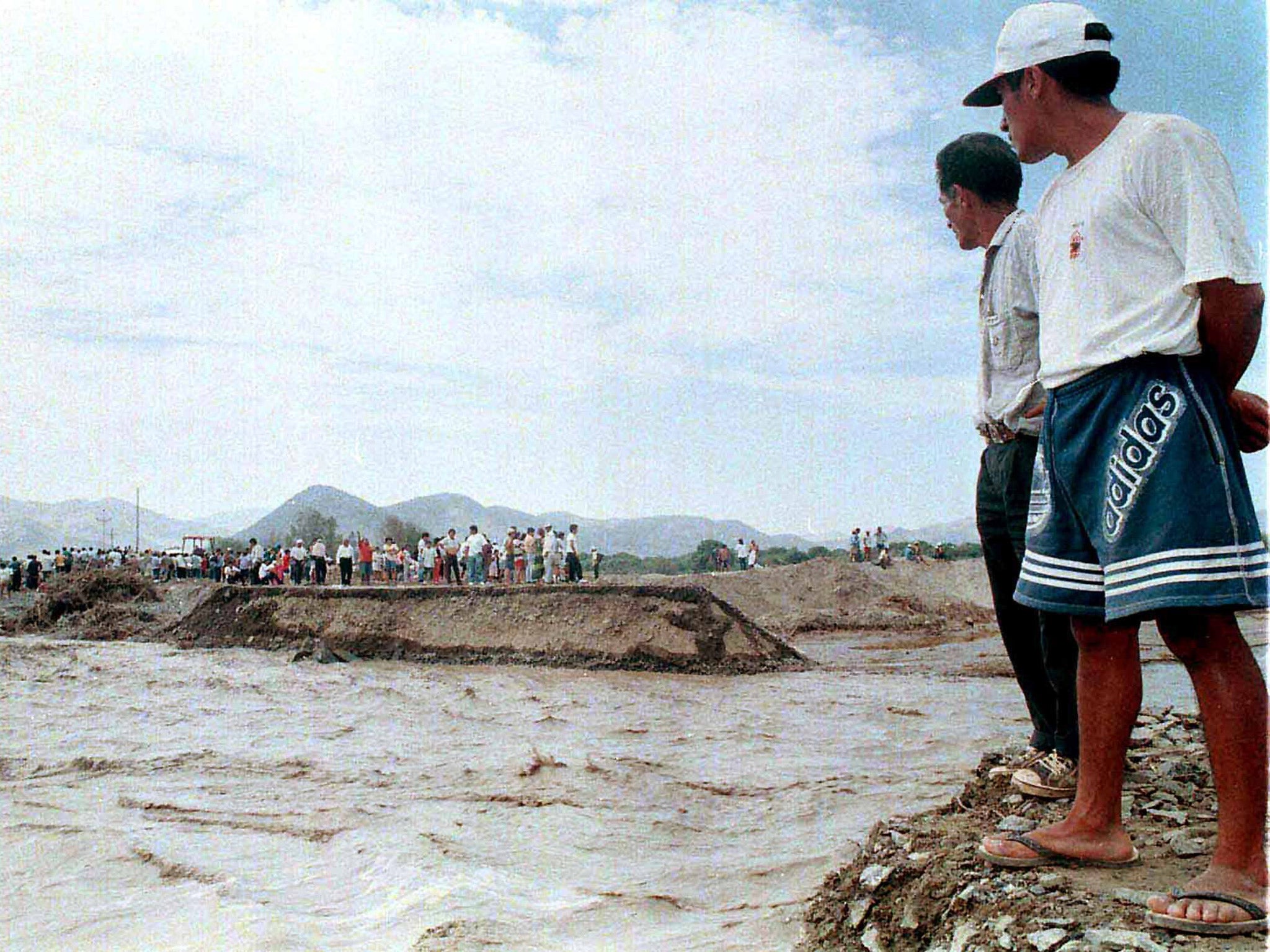 Local Peruviuan residents watch El Nino flood waters from the Nepena River near Huambacho in 1998