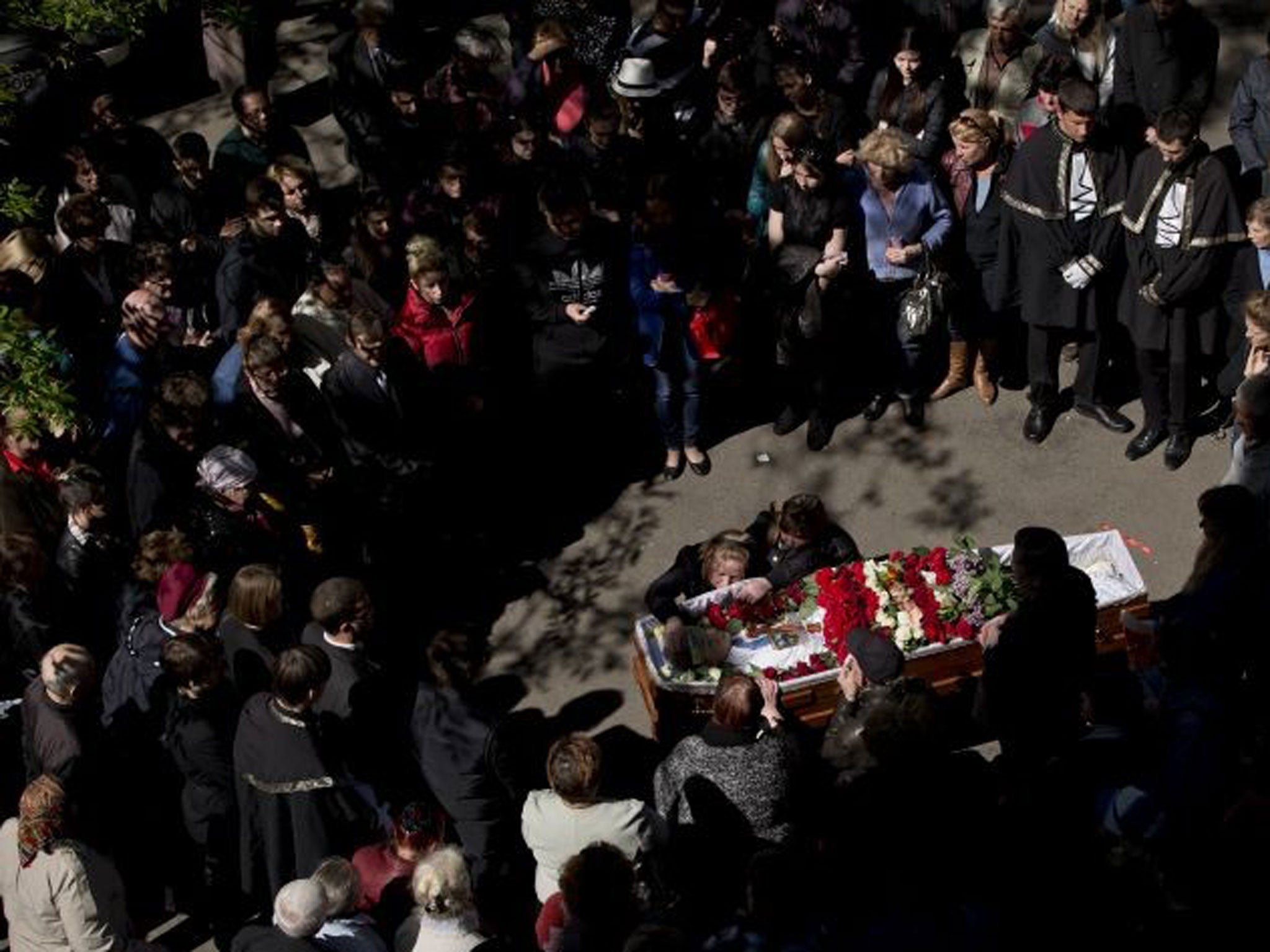 People gather around the coffin of 17 year-old Vadim Papura during a religious service outside the apartment block he lived in, in Odessa, Ukraine, Tuesday, May 6, 2014.
