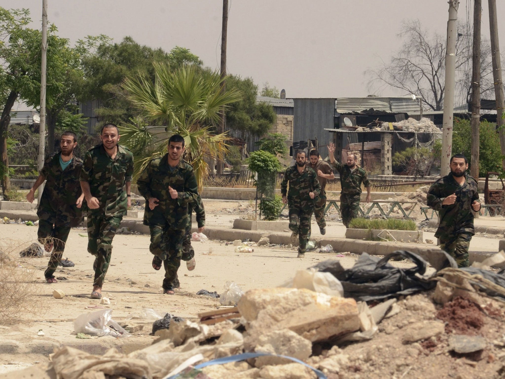 Forces loyal to Syria's President Bashar al-Assad run through Aleppo's Bustan al-Qasr crossing after their release by rebels. They were freed as part of a larger deal which saw the last remaining Syrian rebels in central Homs city evacuate their positions