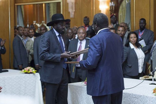 Salva Kiir (L), President of South Sudan, and Riek Machar (R), SPLM Opposition leader, hand over the Cessation of Hostilities treaty over the war in South Sudan