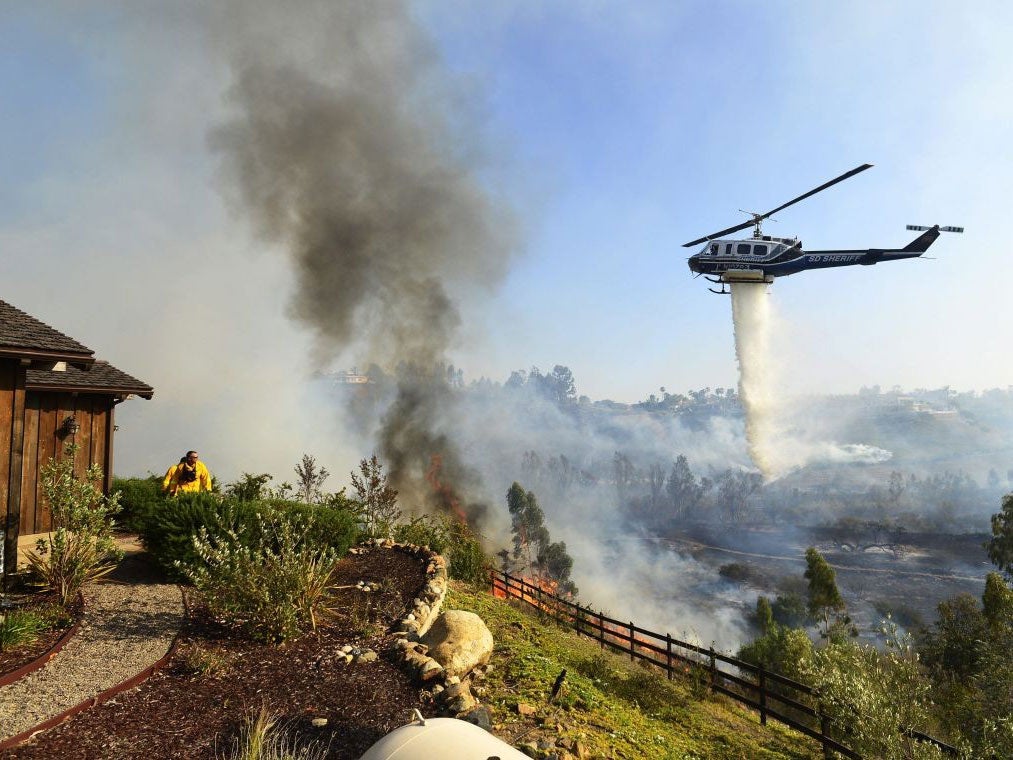 A helicopter drops water near the Rancho Santa Fe neighbourhood during the wildfire north of San Diego, California on 13 May.