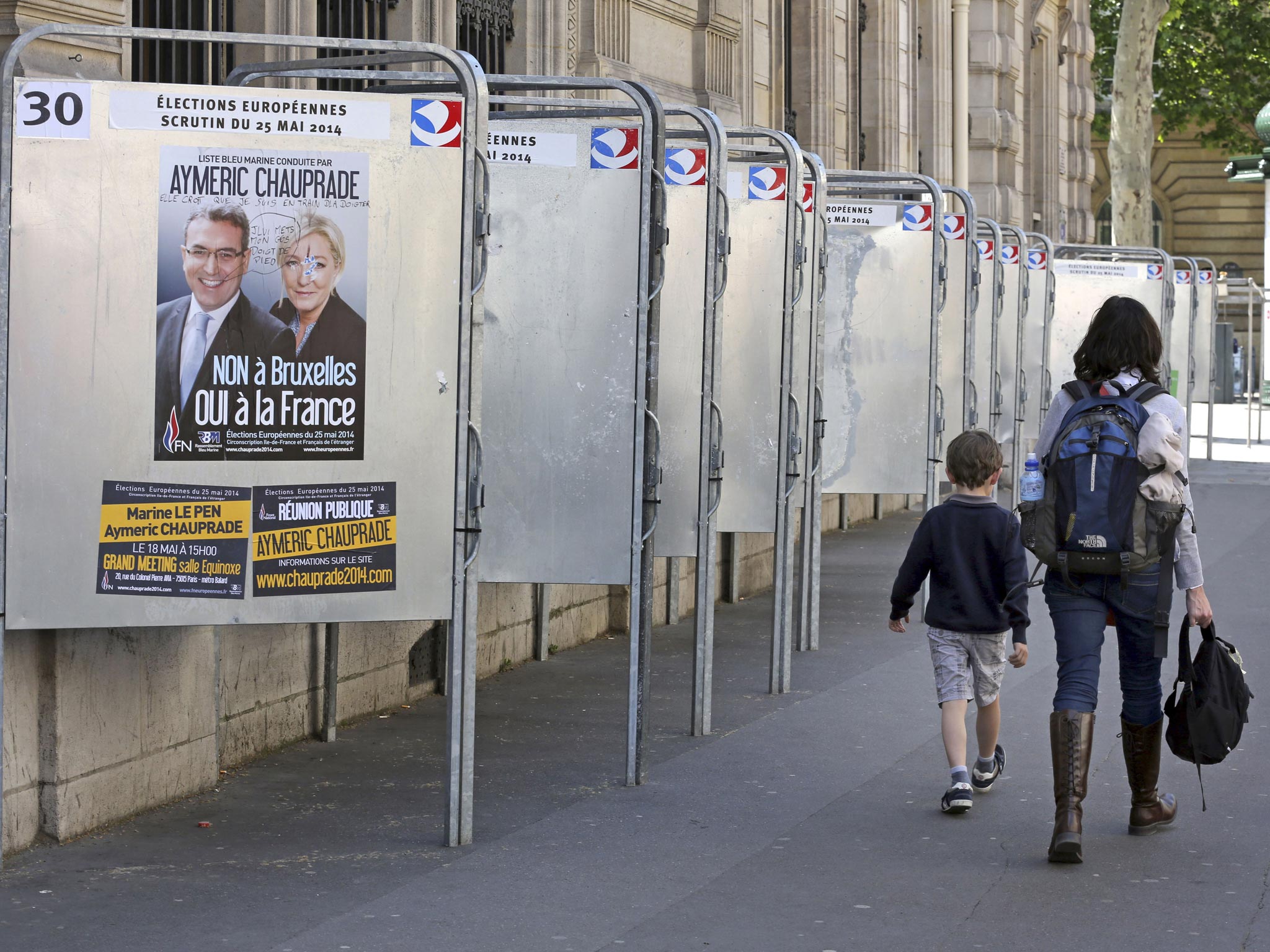 A woman walks past electoral boards for the upcoming European elections in Paris