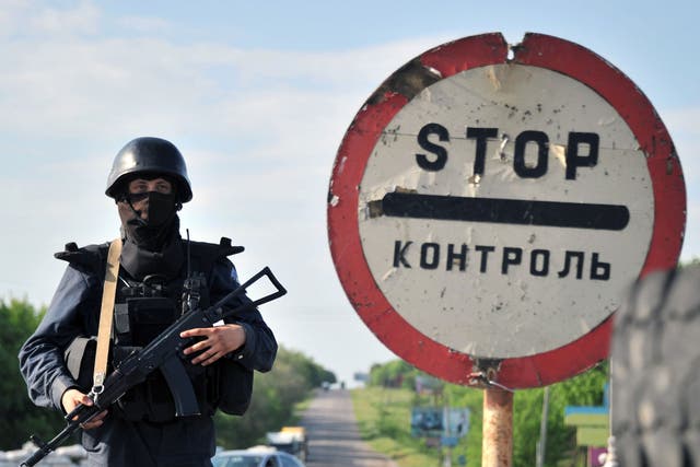 Ukrainian troops stand guard at a checkpoint on the road near the  eastern city of Izum, Donetsk  