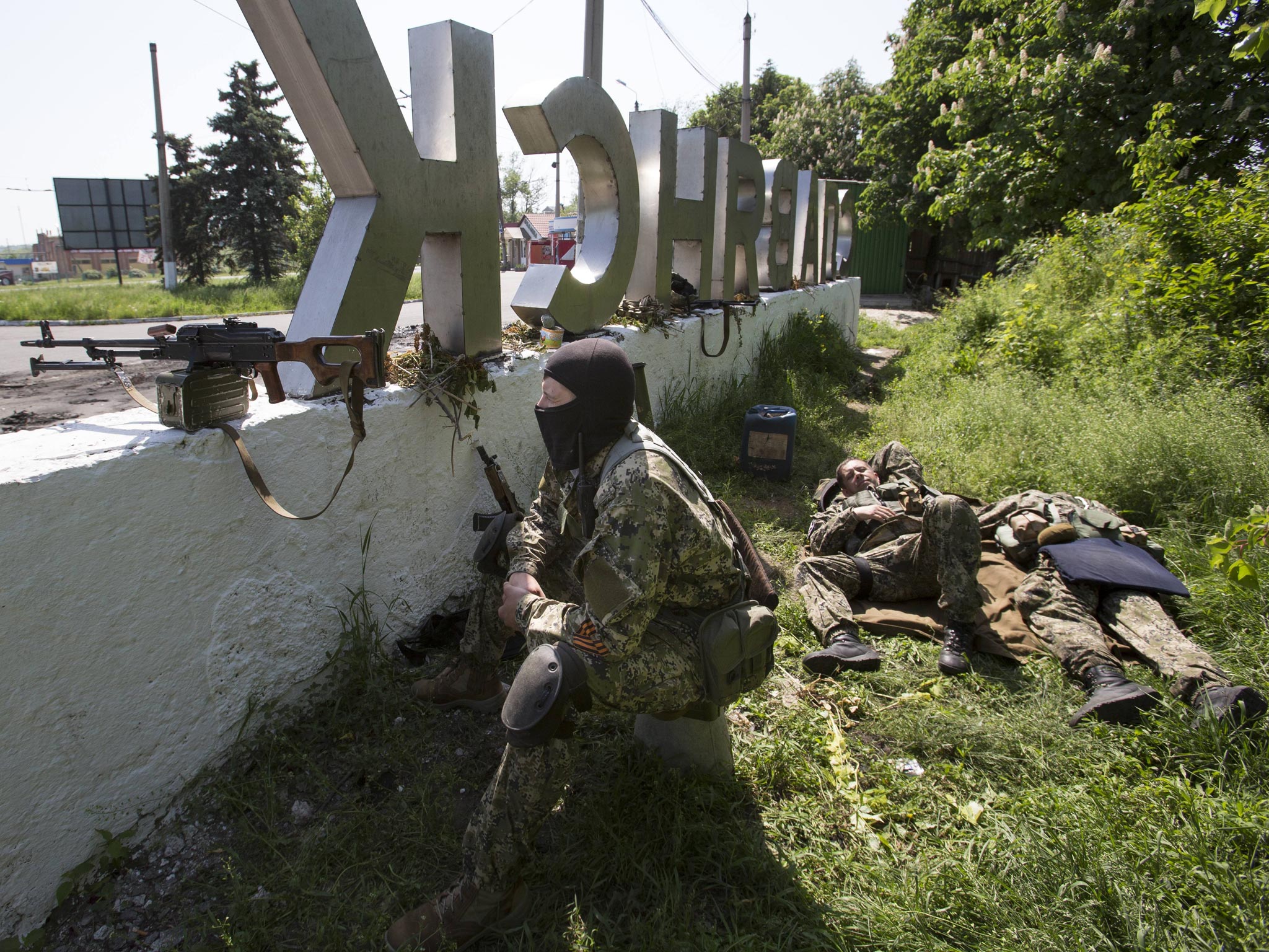 Pro-Russian gunmen take their position behind a sign with the word ‘Slovyansk’, at a checkpoint blocking the major highway