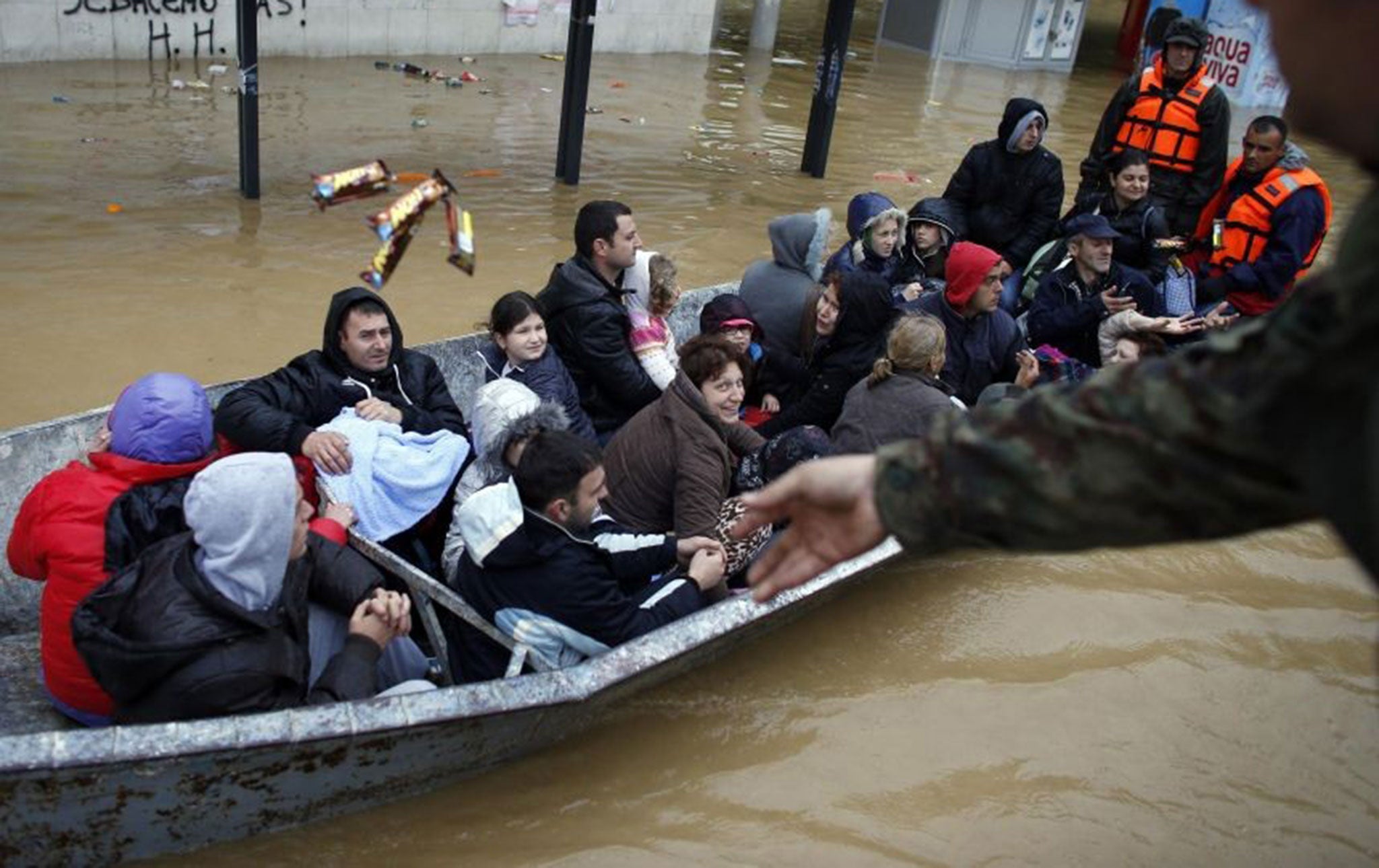 A Serbian army soldier throws candy bars to people on a boat as the flooded town of Obrenovac, east from Belgrade, is evacuated