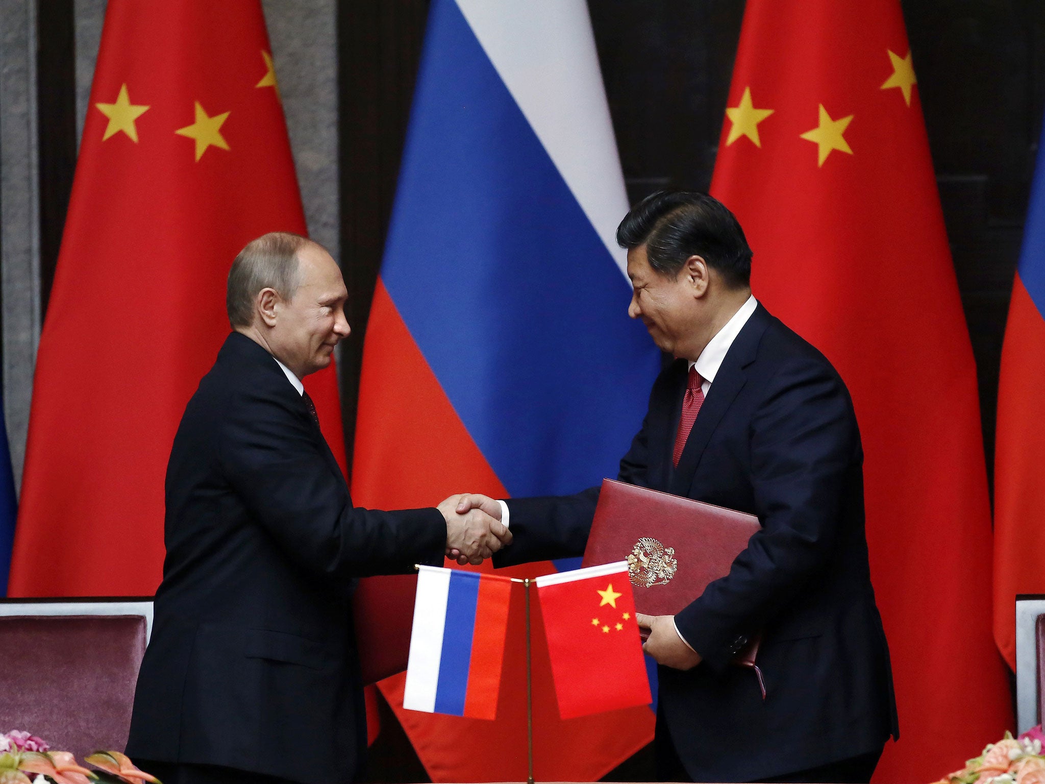 Russia's President Vladimir Putin, left, and China's President Xi Jinping shake hands during a bilateral meeting in Shanghai