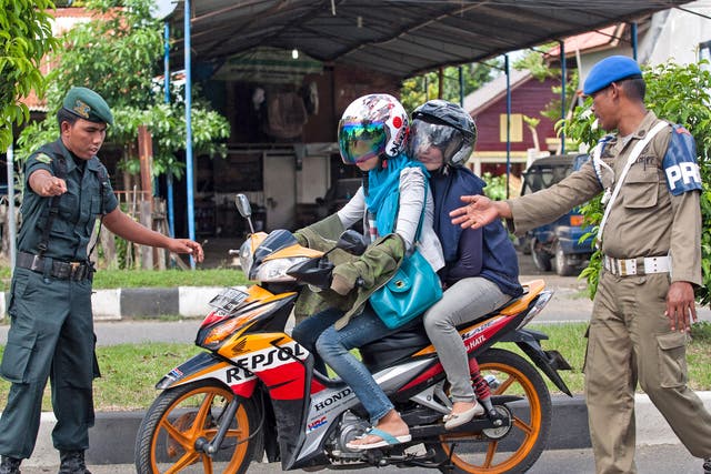 Sharia police stop a couple during an operation against women wearing tight jeans in Banda Aceh