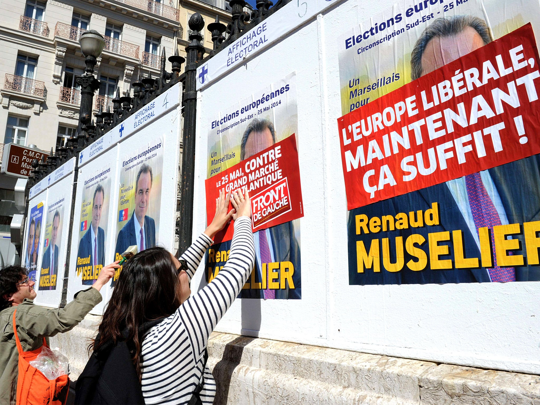 French 'Front de Gauche' ('Left Front') activists plaster European election posters of their party on top of those of the right-wing UMP party, in Marseille (Getty)