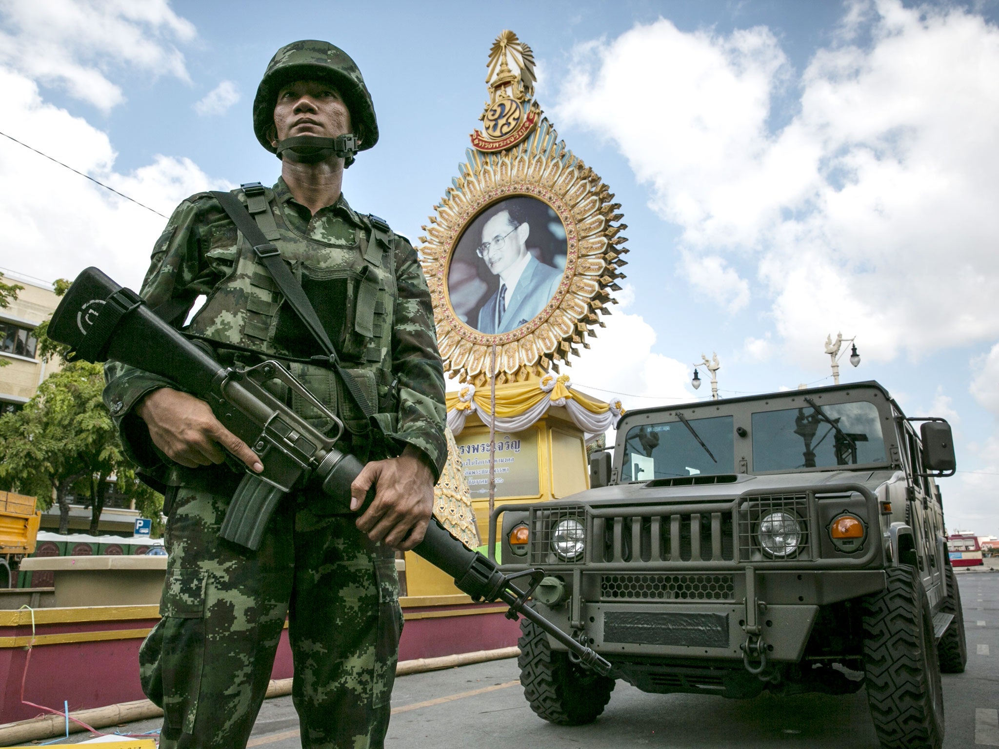 A Thai soldier stands in front of a portrait of Thai King Bhumibol Adulyadej as he patrols near government buildings in Bangkok