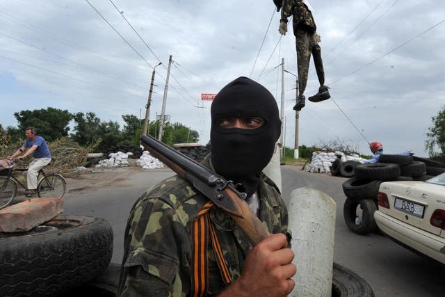 A masked pro-Russian gunman guards at a check-point near the eastern Ukrainian city of Slavyansk on Friday. At least five were killed yesterday in fighting near Ukraine’s eastern hub of Donetsk