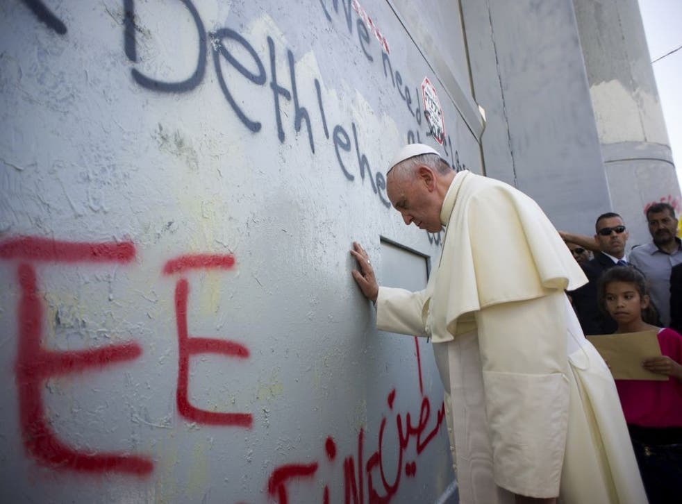 Pope Francis prays at the wall that divides Israel from the West Bank, on his way to celebrate a mass in Manger Square in Bethlehem