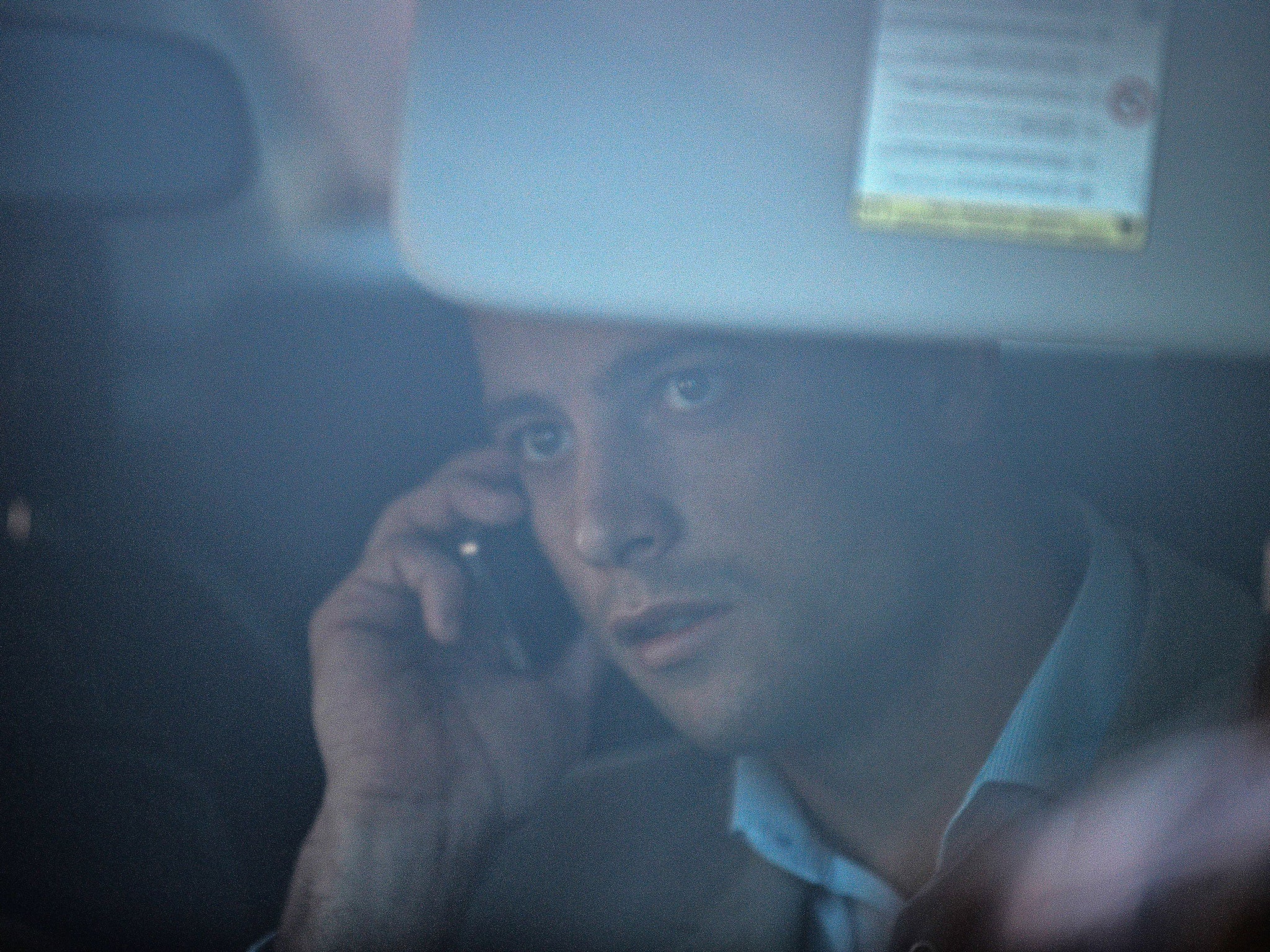 Oscar Pistorius talks on a mobile phone while arriving in a car at the Weskoppies Psychiatric Hospital on May 26 2014 in Pretoria