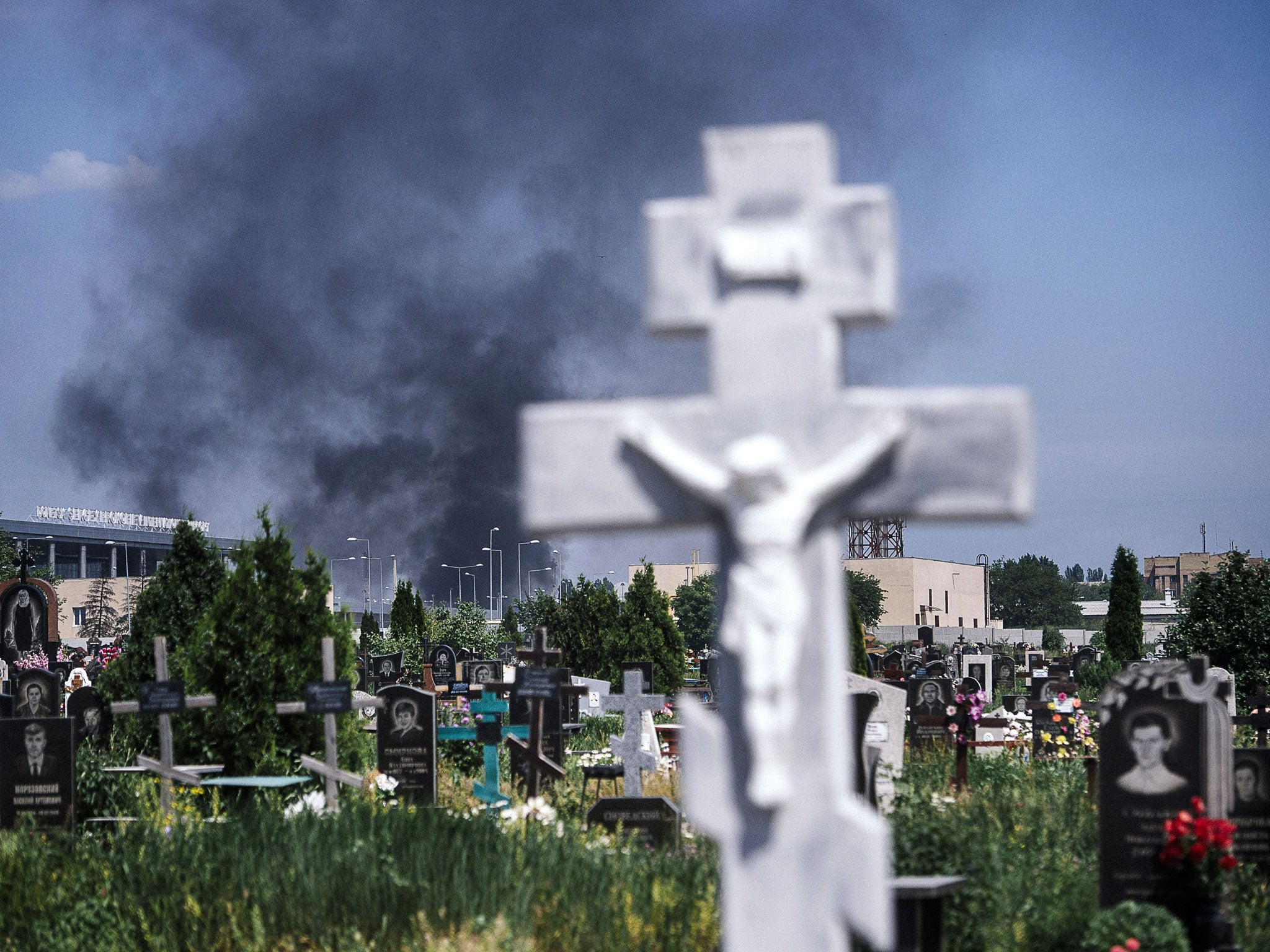 Black smoke billows from Donetsk international airport, seen behind a cemetery, during heavy gun battle between the Ukrainian army and pro-Russian militants in the eastern Ukrainian city of Donetsk on May 26, 2014