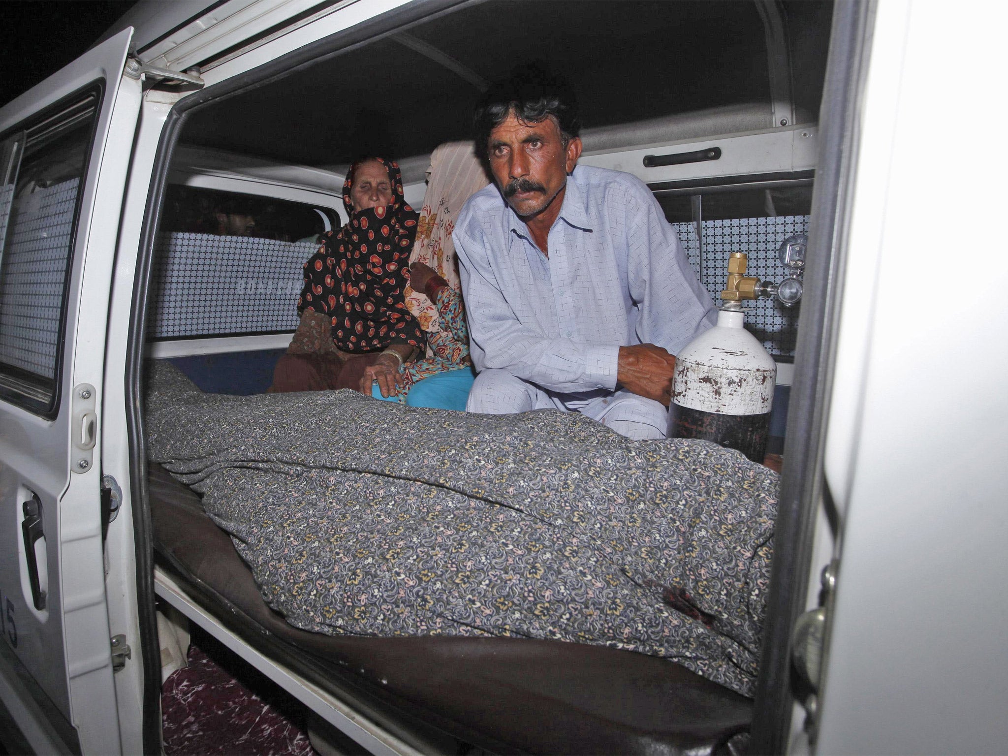 Mohammad Iqbal sits next to his wife Farzana's body in an ambulance in Lahore