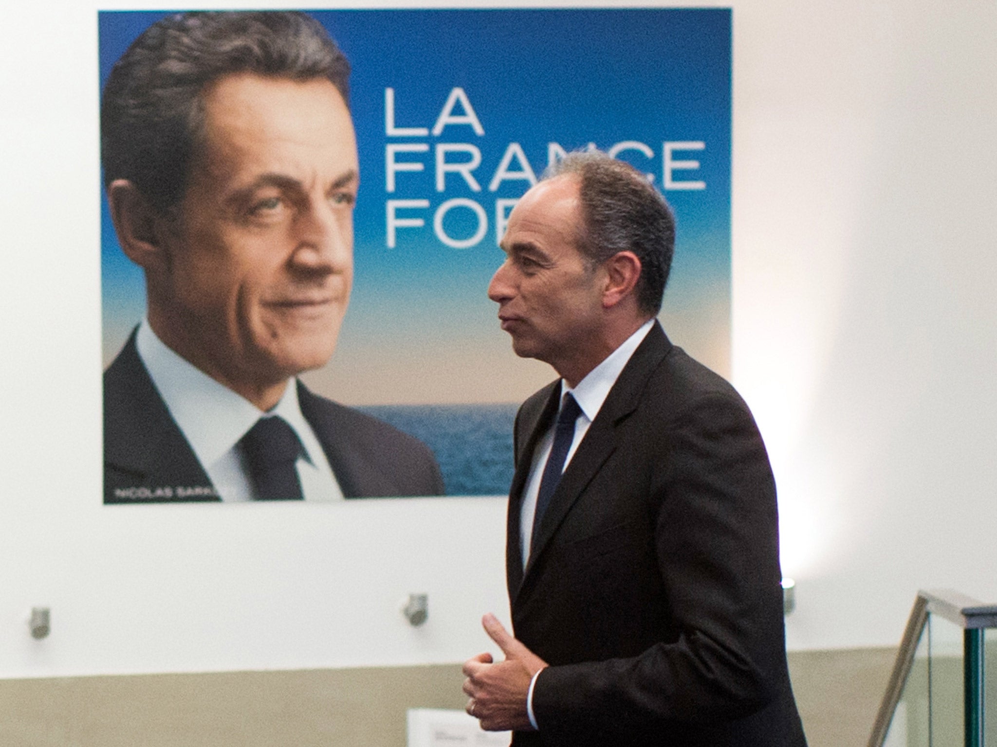Jean-Francois Cope walks by a presidential campaign poster of former French president Nicolas Sarkozy, earlier this year