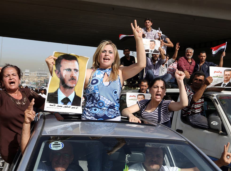 Syrian refugees near the embassy in Beirut display pictures and chant slogans in support of President Bashar al-Assad