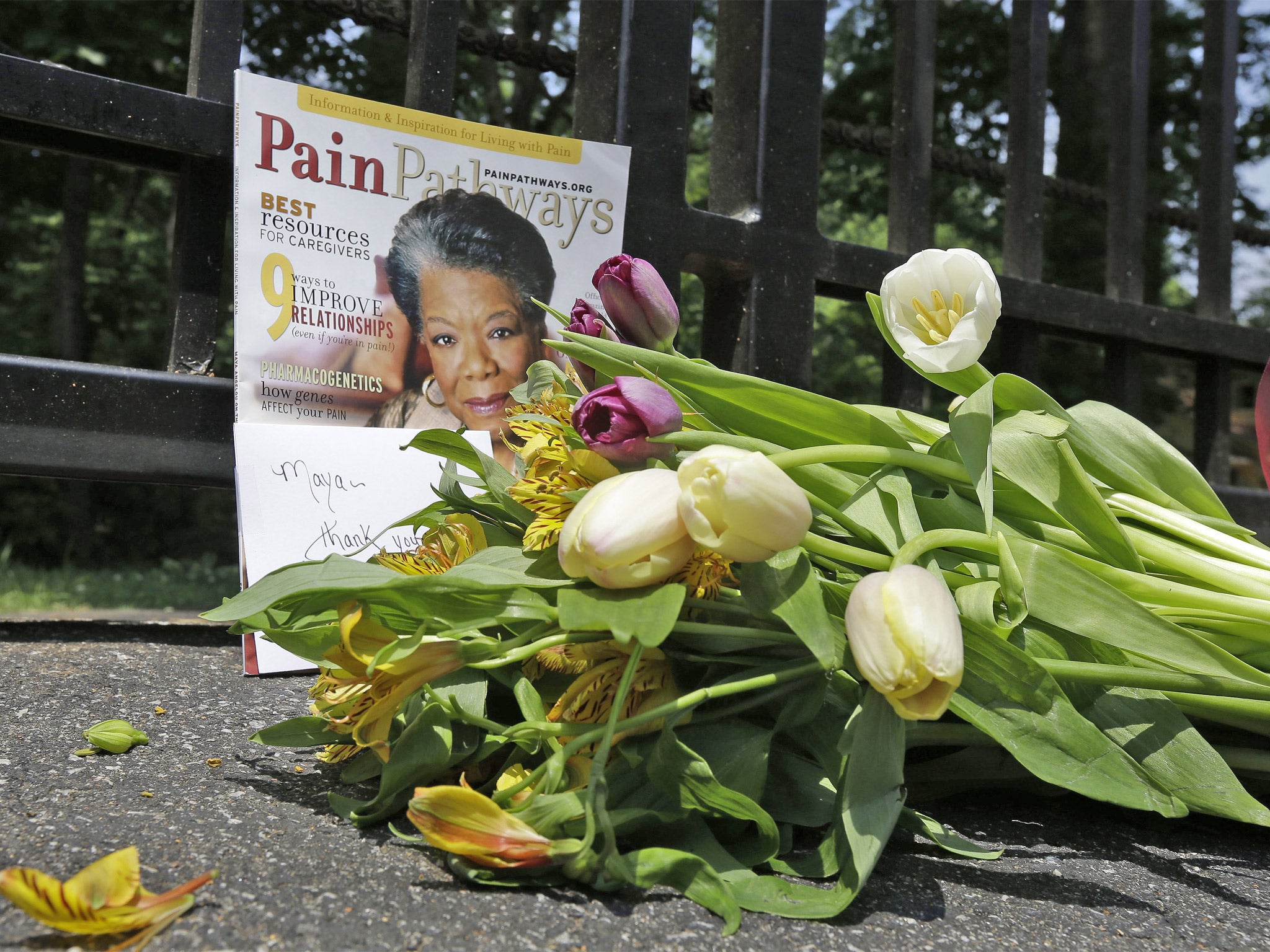 A bouquet of flowers and a magazine showing Maya Angelou on the cover lie outside her home