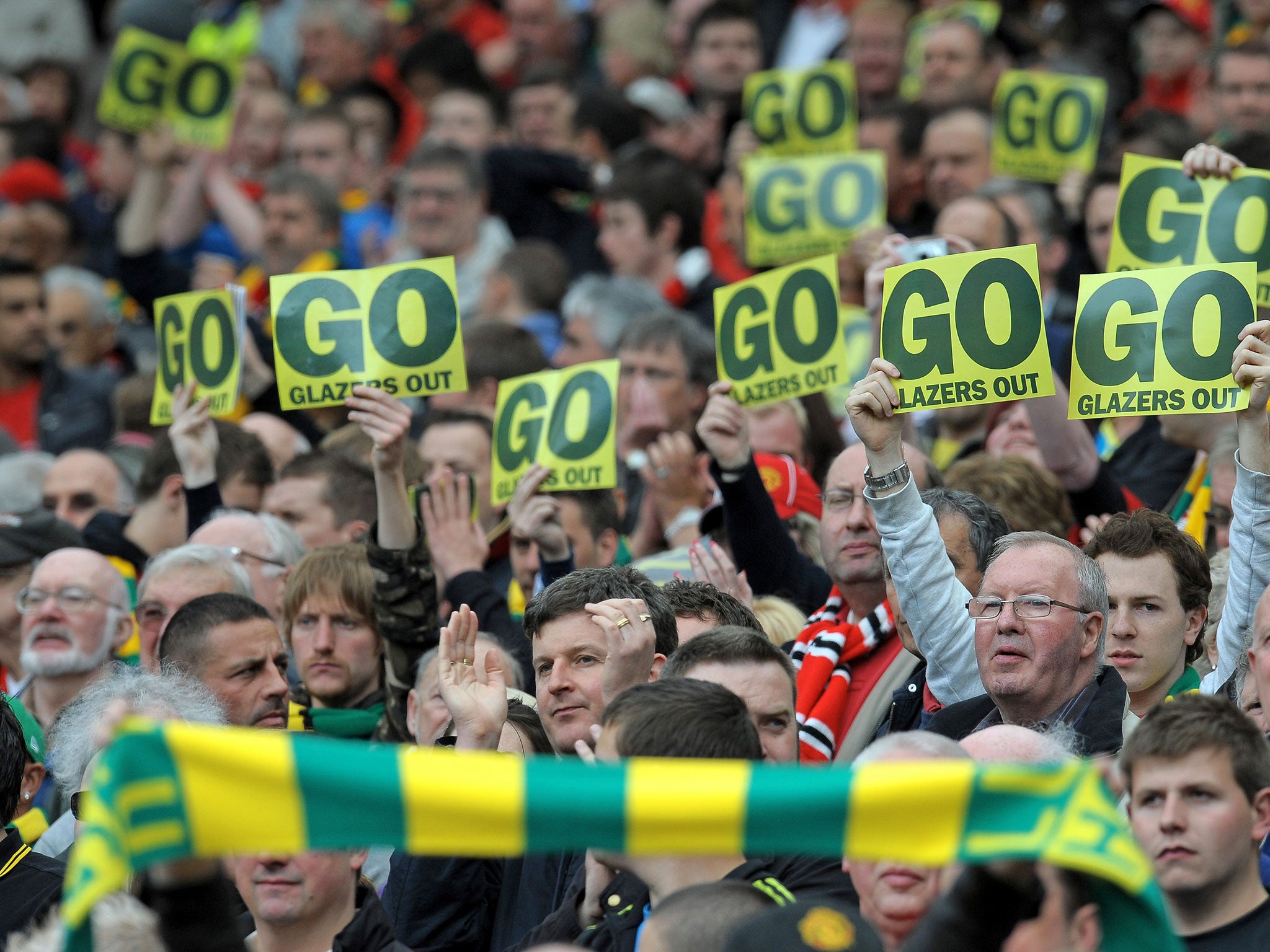 Supporters hold posters opposing Manchester United's US owners