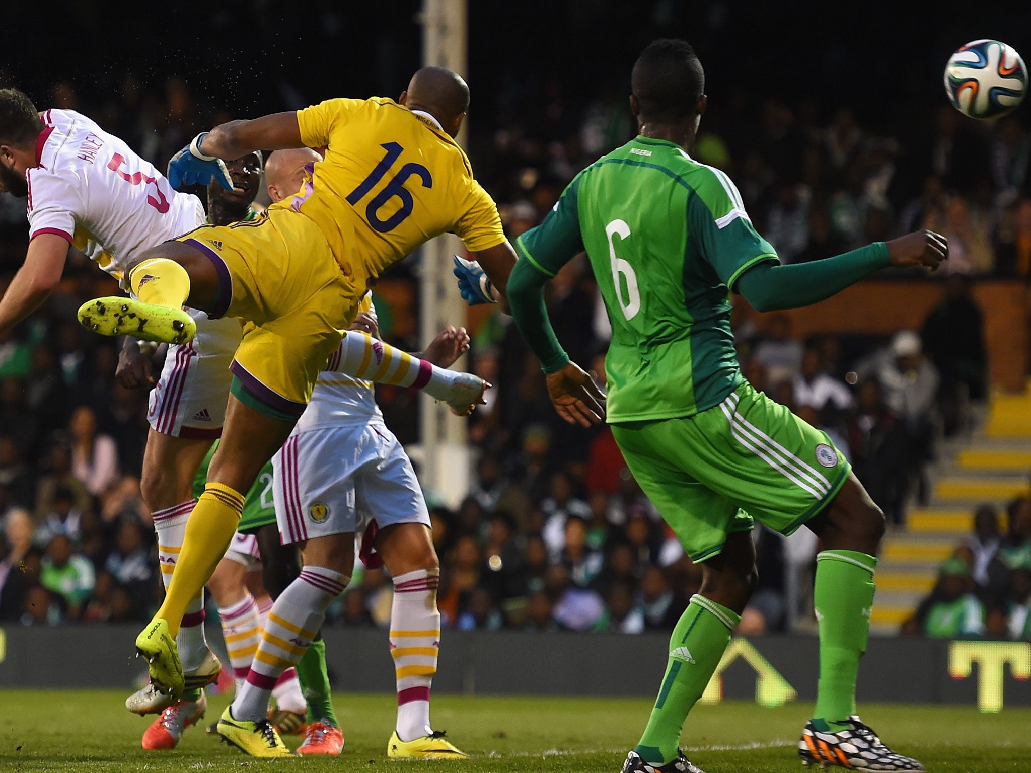 Nigeria goalkeeper Austine Ejide (#16) scoops the ball into his own net while competing with Scotland's Grant Hanley (#5)