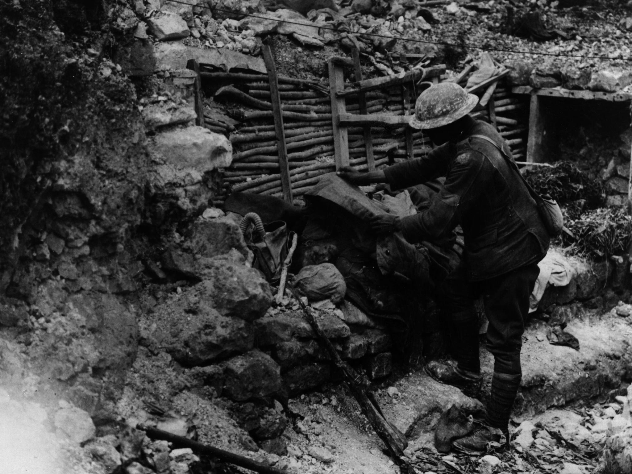 A British soldier covers a dead German on the firestep of a trench near the Somme