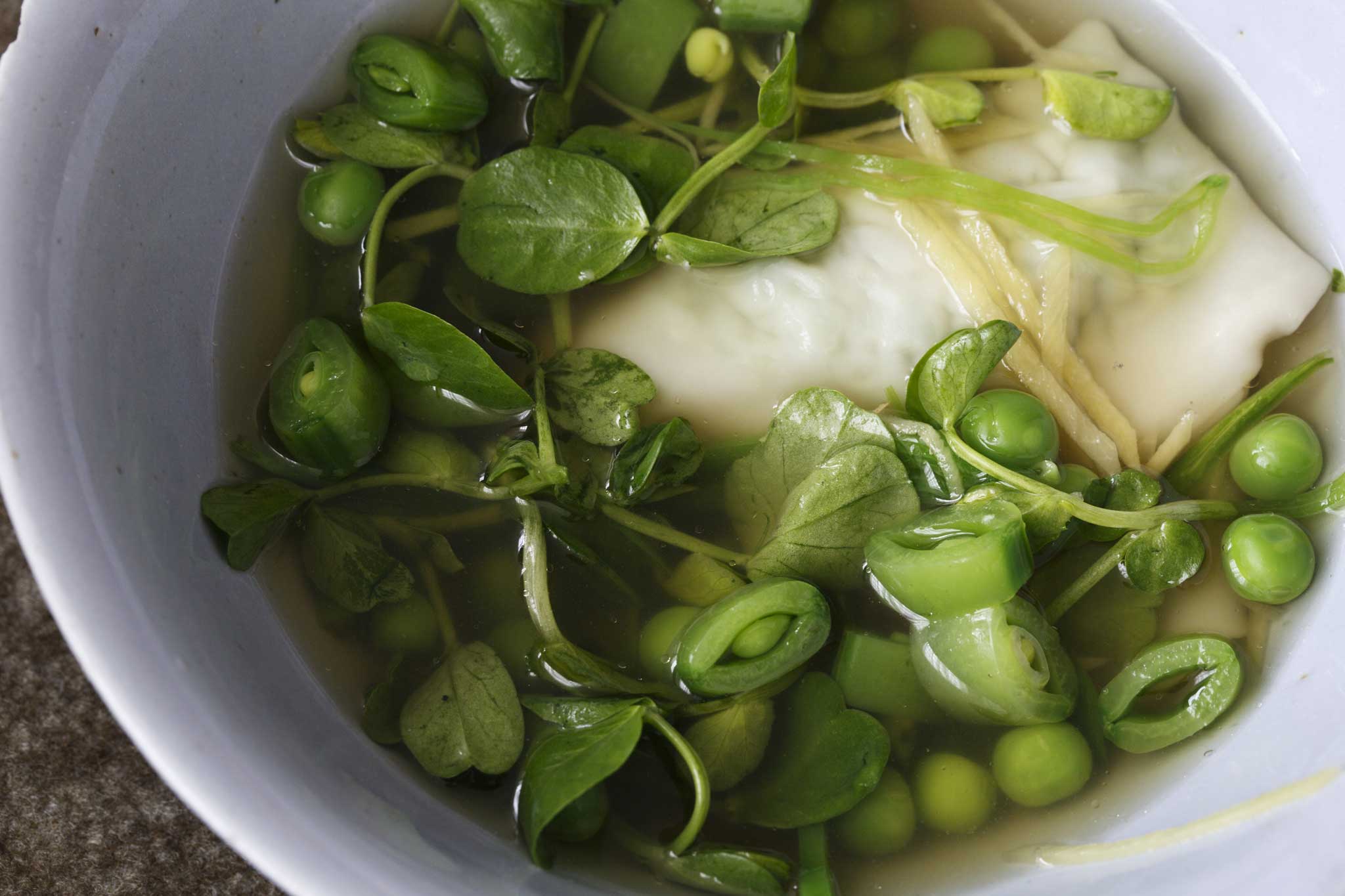 Goyza pea dumplings in broth with peas, pea shoots and sliced beans