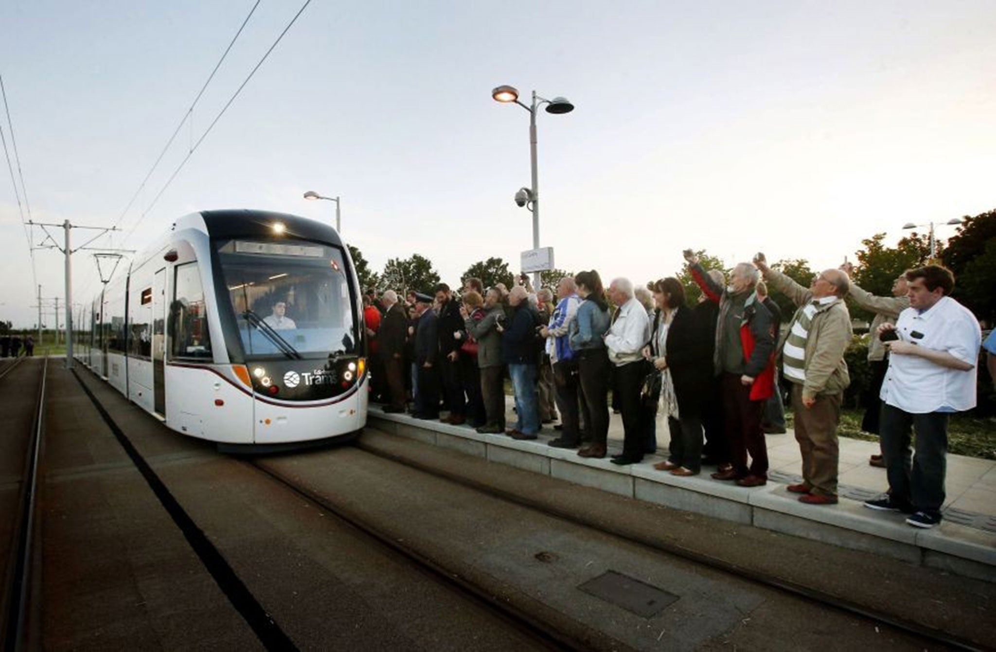Passengers wait to board the first tram at the Gyle shopping centre stop in Edinburgh