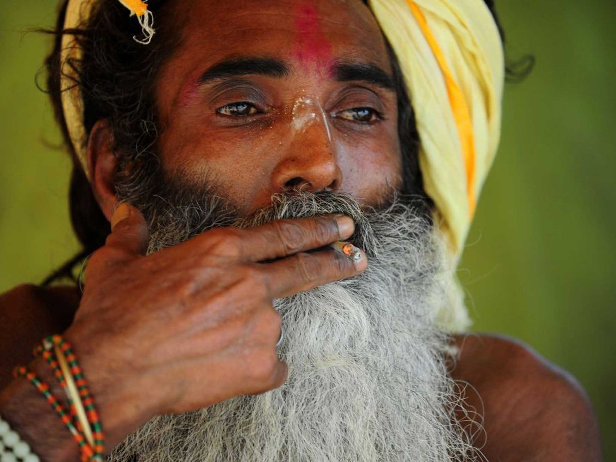 Holy smoke: A holy man enjoys a cigarette in India