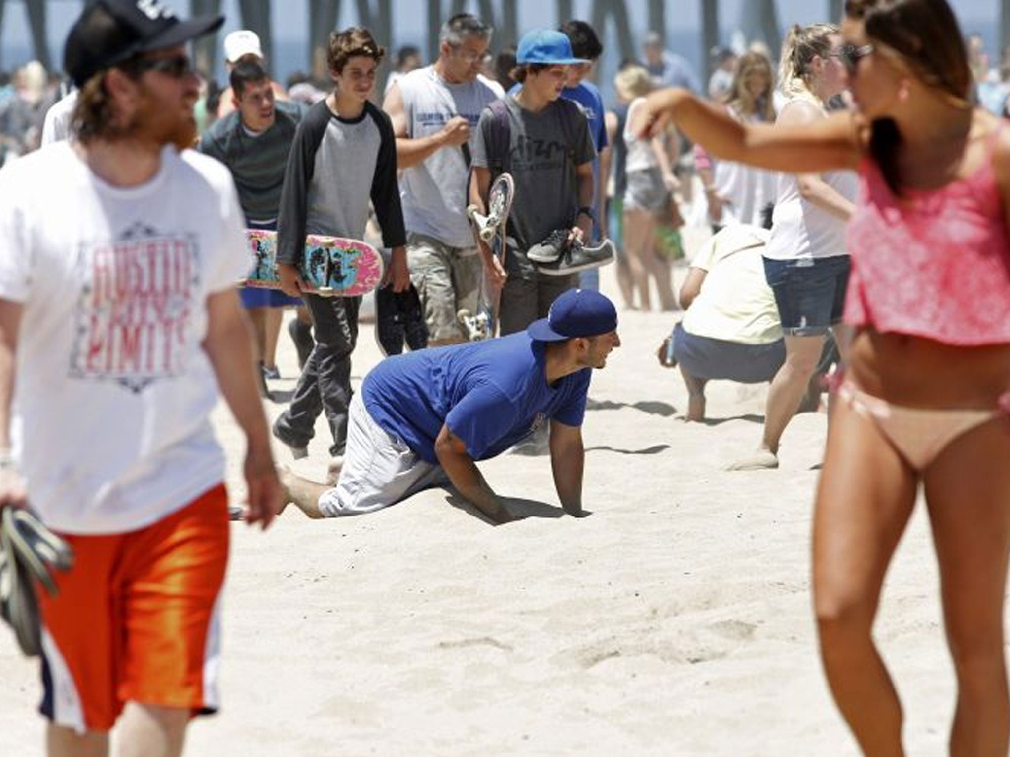 A man searches in the sand for one of 36 buried plastic Angry Bird orbs filled with hidden cash in Hermosa Beach, California