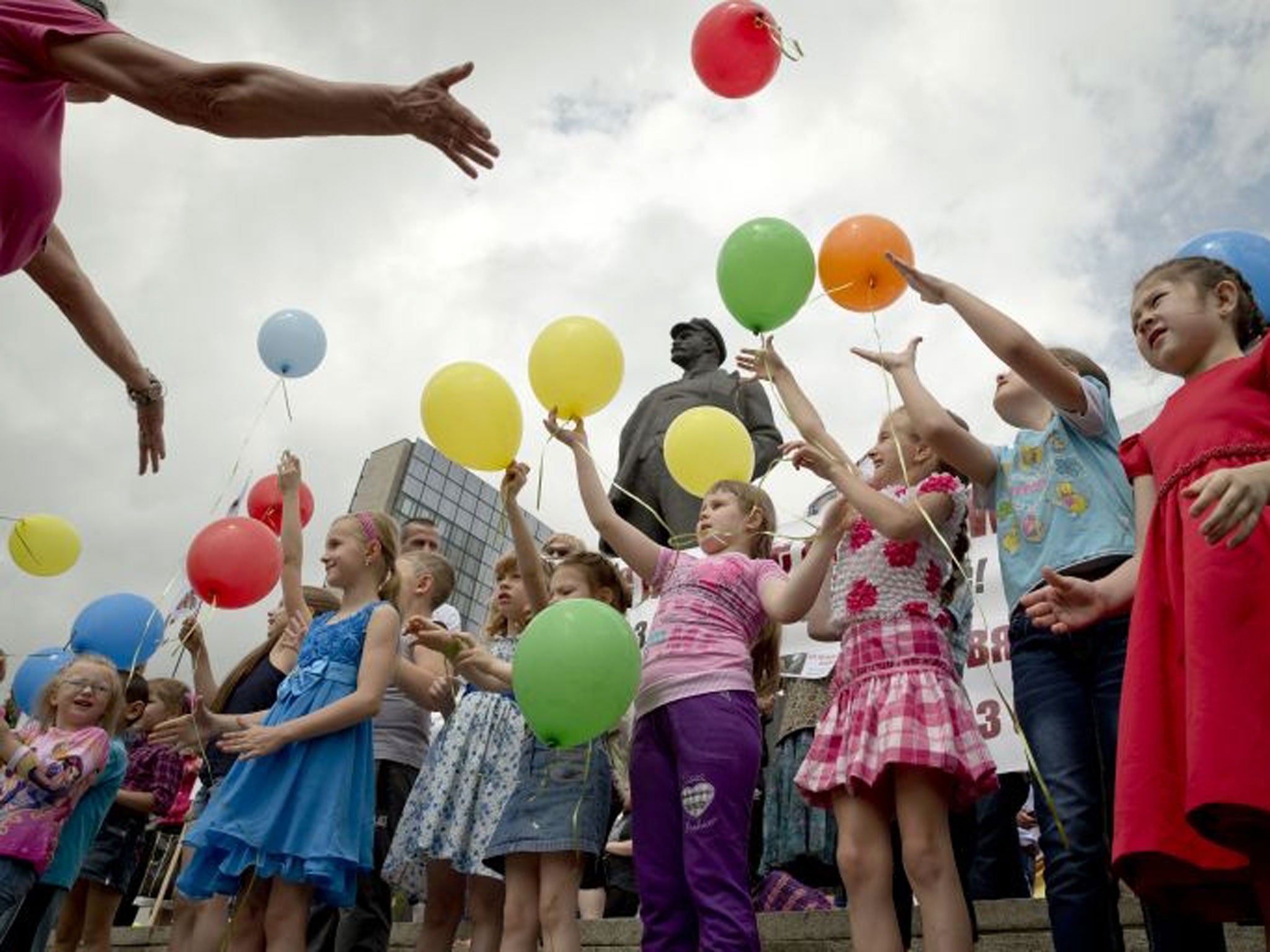Children release balloons, back dropped by a statue of Lenin, during a pro-Russian rally in Donetsk, Ukraine, Sunday, June 1, 2014.