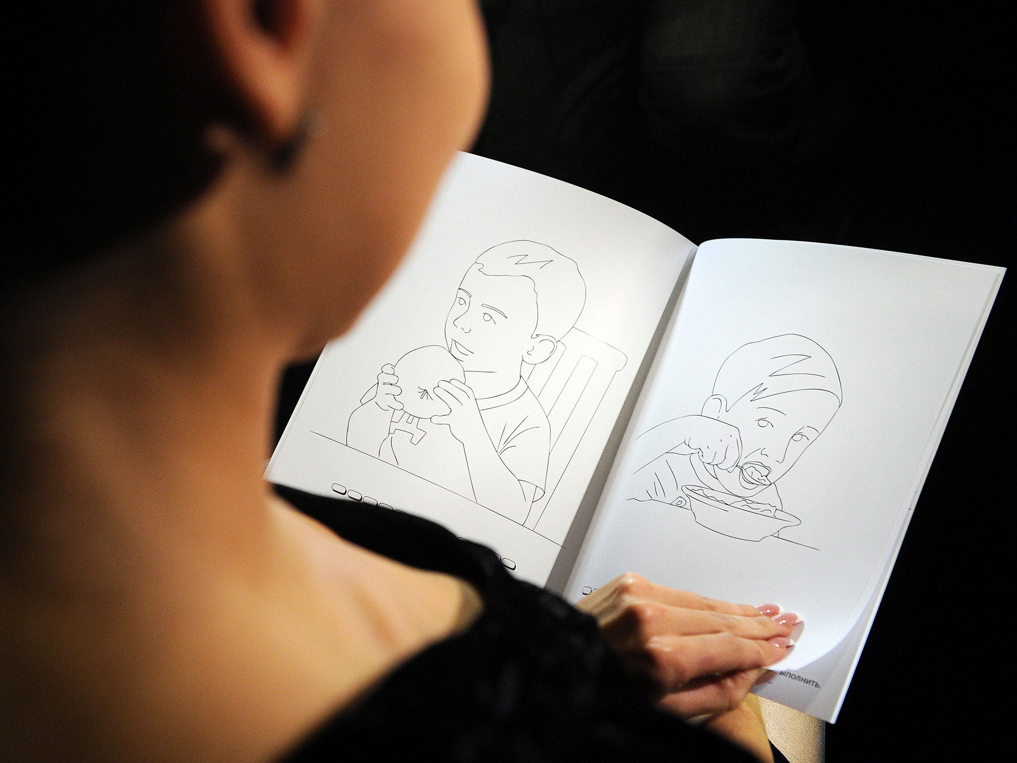 A woman holds a colouring book during a presentation in Moscow on October 6, 2011. A Moscow publishing house has released a children's colouring book in which two boys called Vova and Dima, closely resembling Prime Minister Vladimir Putin and President Dm