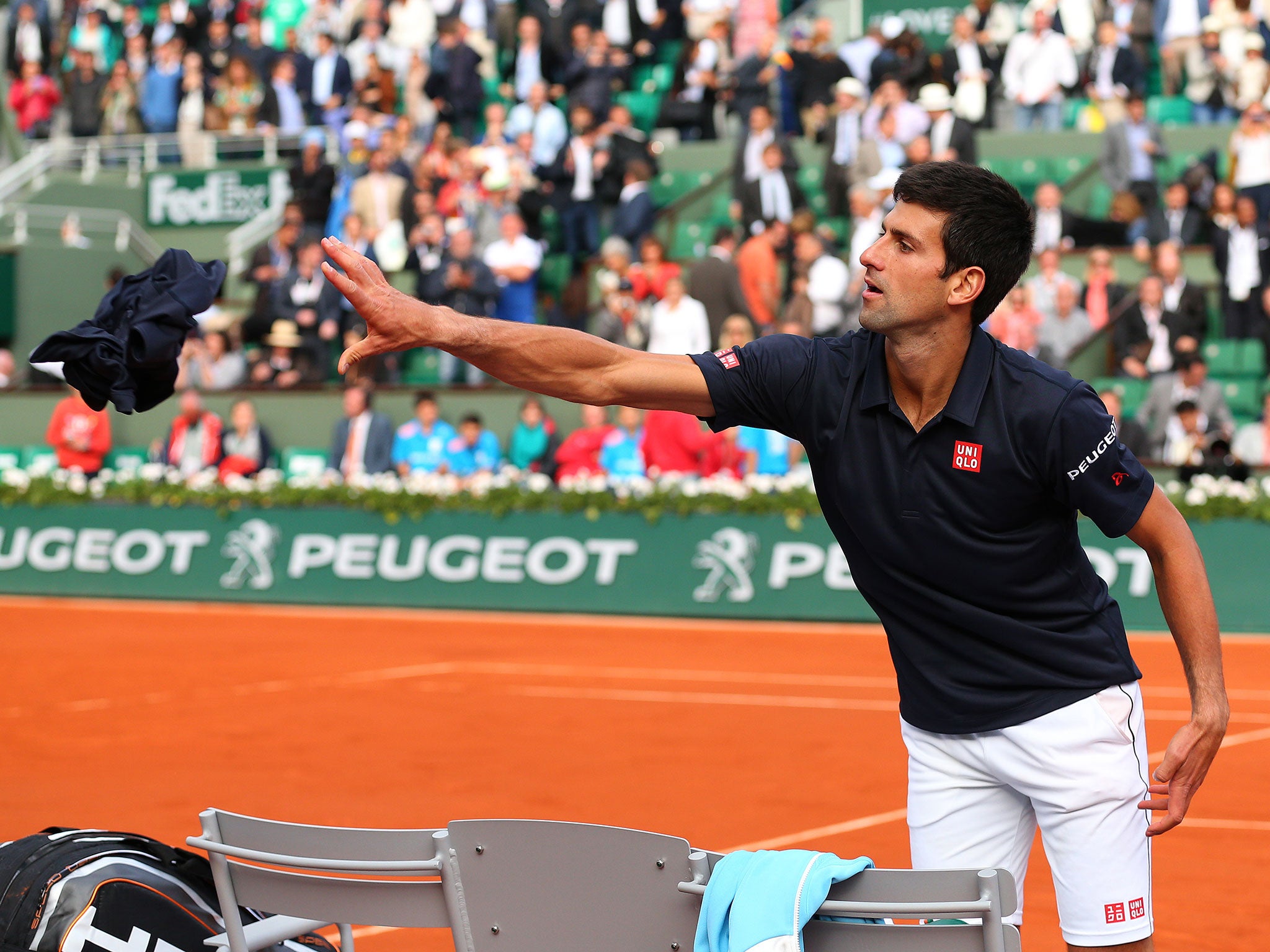 Novak Djokovic of Serbia throws a shirt into the crowd as he celebrates victory in his men's singles quarter-final against Milos Raonic of Canada