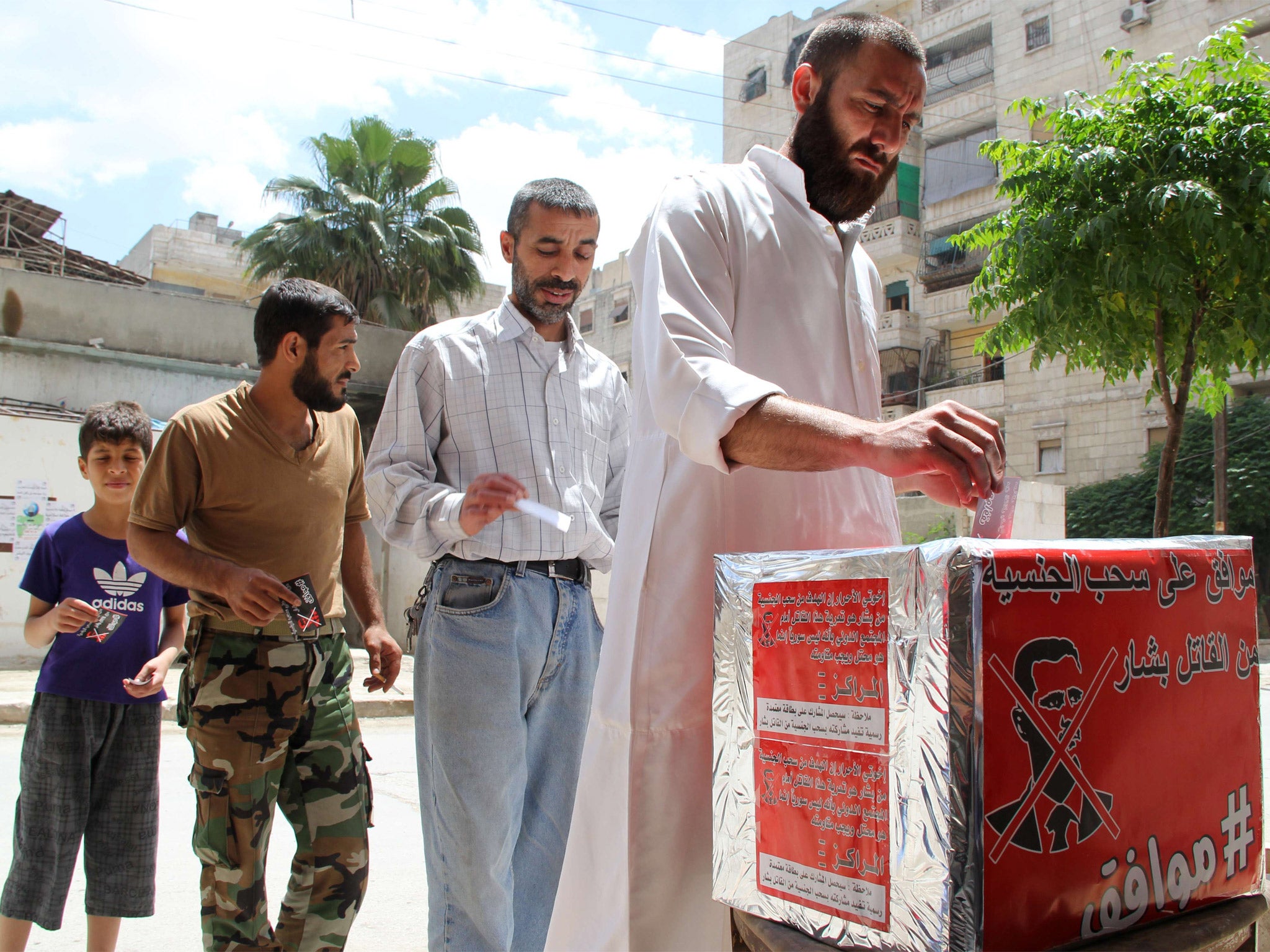 Syrian men pretend they are casting their votes during a mock election calling for the 'criminal' Syrian President Bashar al-Assad to the stripped of his nationality (Getty)