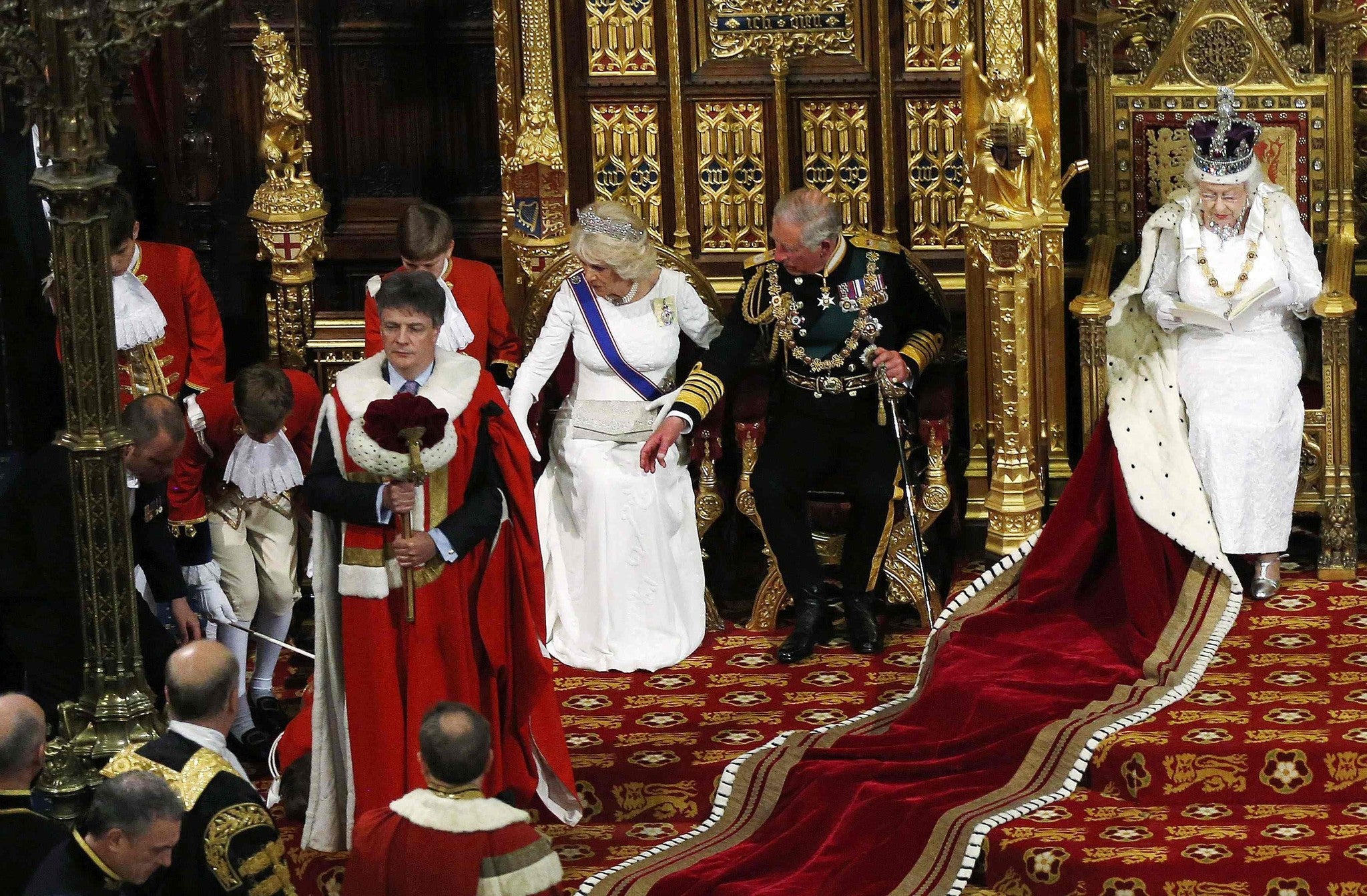 Britain's Prince Charles, Prince of Wales (C) and Camilla, Duchess of Cornwall (L) reach towards a page boy who fainted as Britain's Queen Elizabeth (R) delivers the Queen's Speech in the House of Lords during the State Opening of Parliament at the Palace