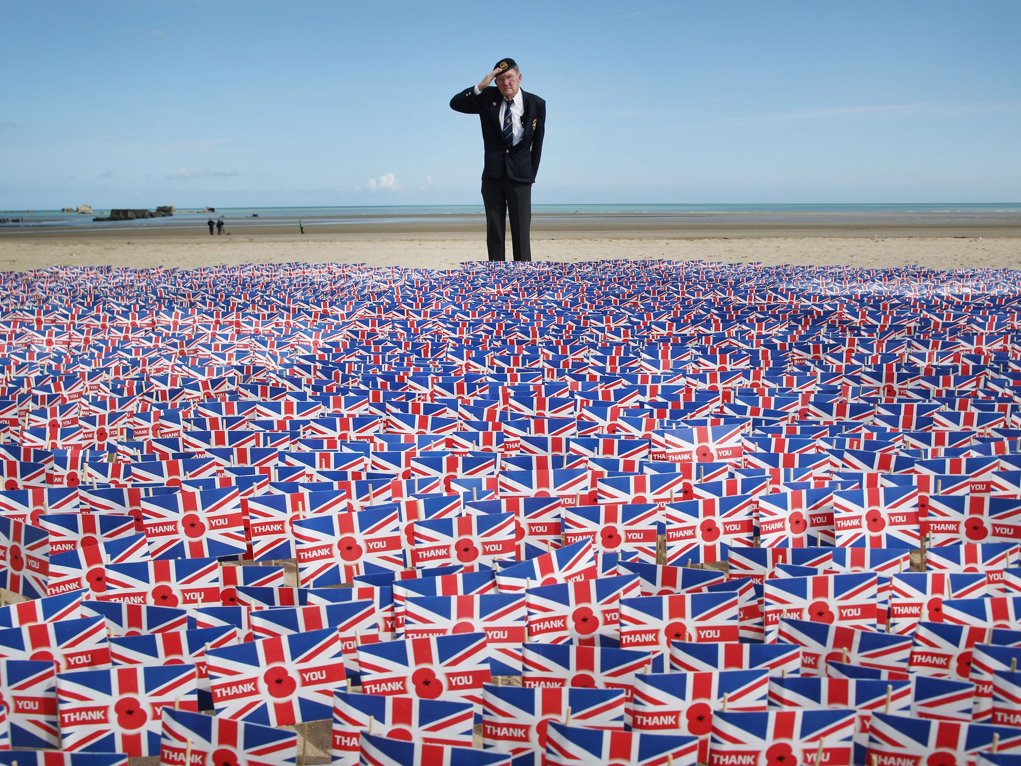 WW2 veteran Fred Holborn, from the Fleet Air Arm, salutes as he looks at British Legion Union flags carrying thank you messages planted in the sand on Gold beach near Asnelles, France. 20,000 paper flags are being planted. Each one carries a personal mess