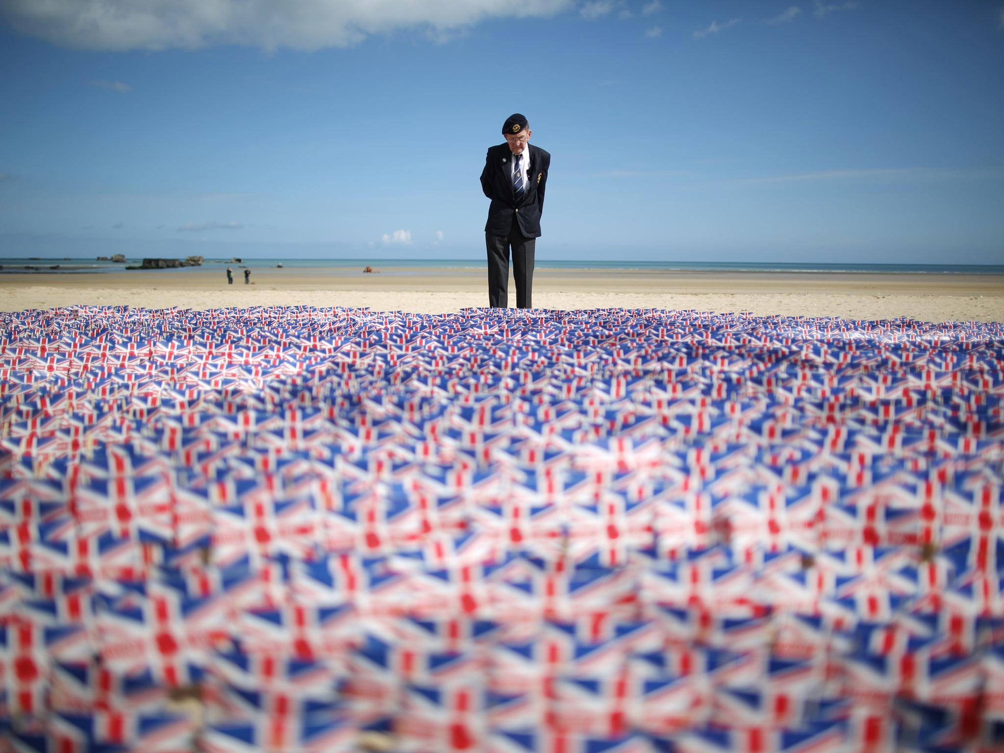 WW2 veteran Fred Holborn, from the Fleet Air Arm, looks at British Legion Union flags carrying thank you messages planted in the sand on Gold beach